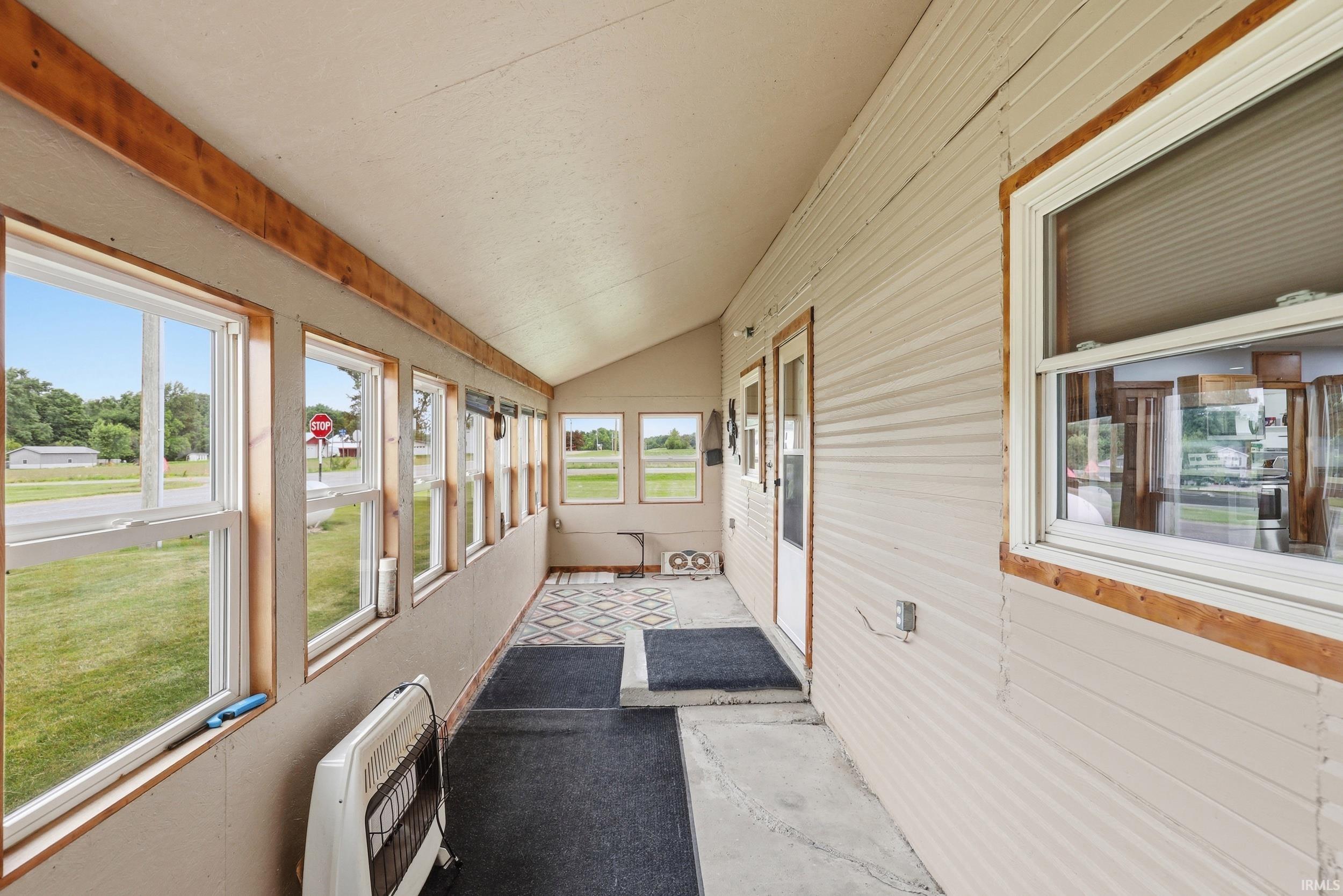 Enclosed porch featuring multiple windows, a sloped ceiling, and wood-finish trim