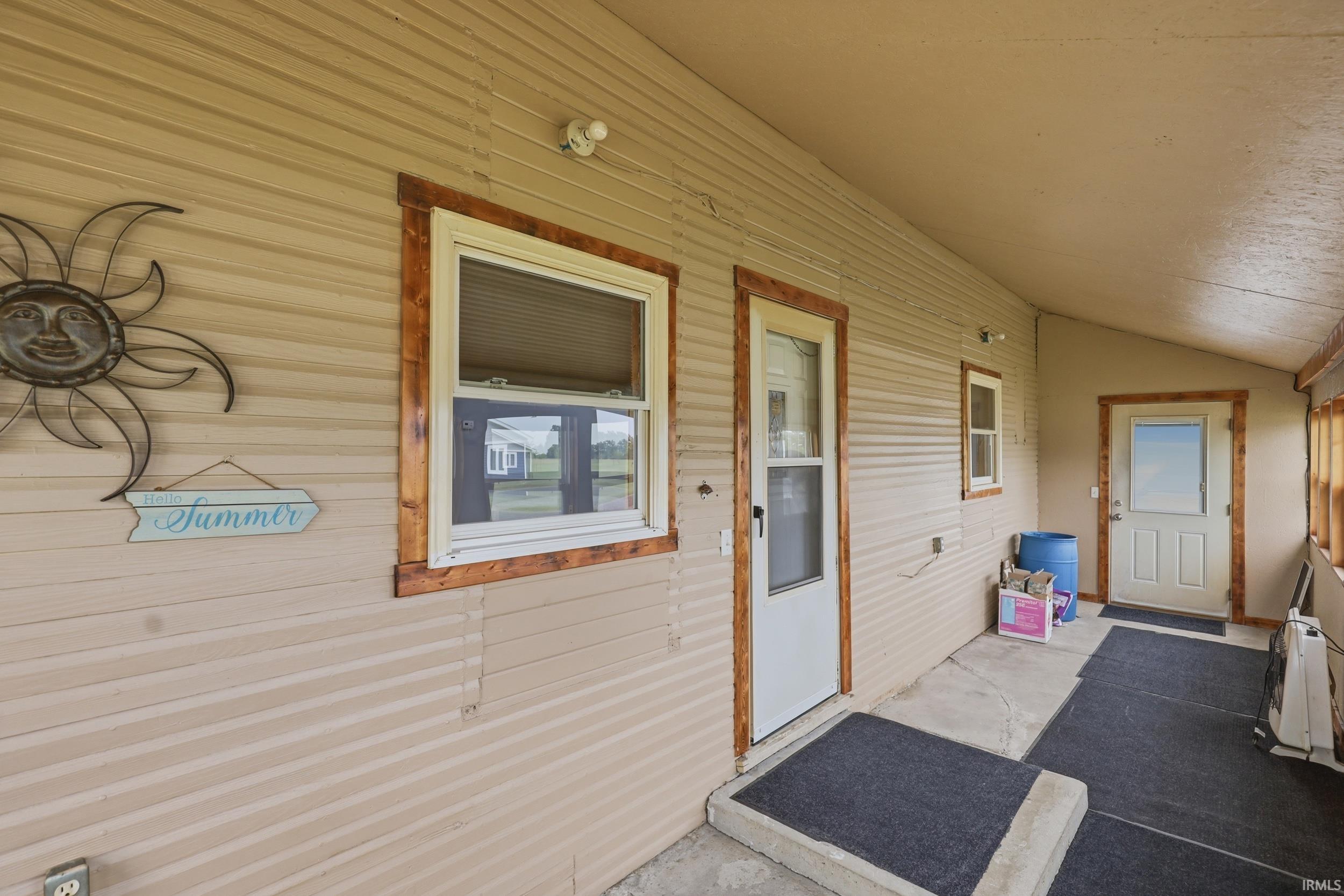 Covered porch with light beige horizontal siding and contrasting natural wood trim around windows and doors