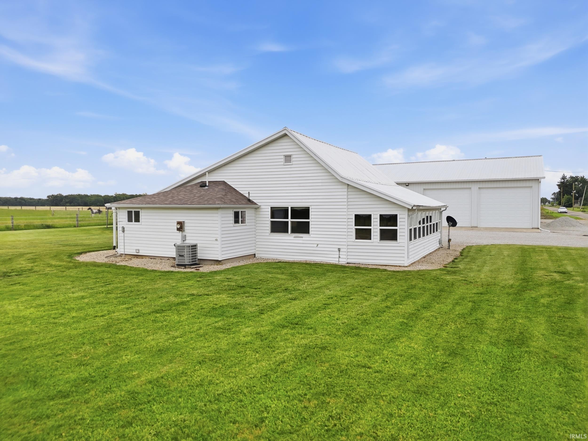 White siding residence with a metal roof and an extensive green lawn