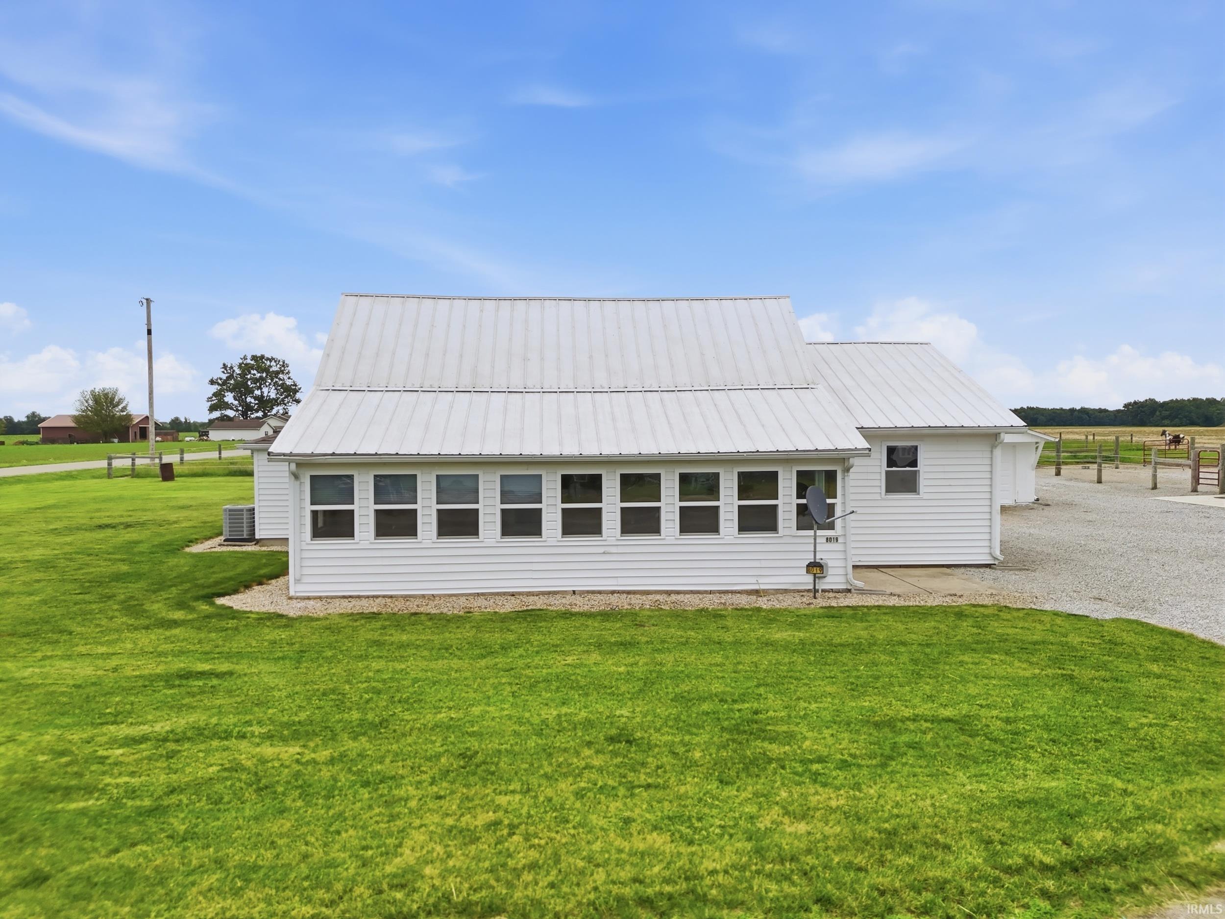 White residential structure featuring a white metal roof, white siding, and multiple windows