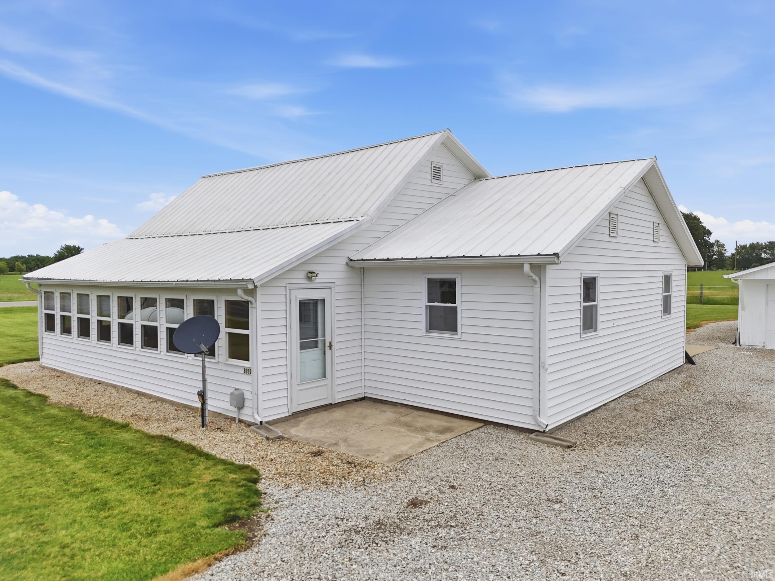 White siding exterior with a metal roof and an enclosed porch