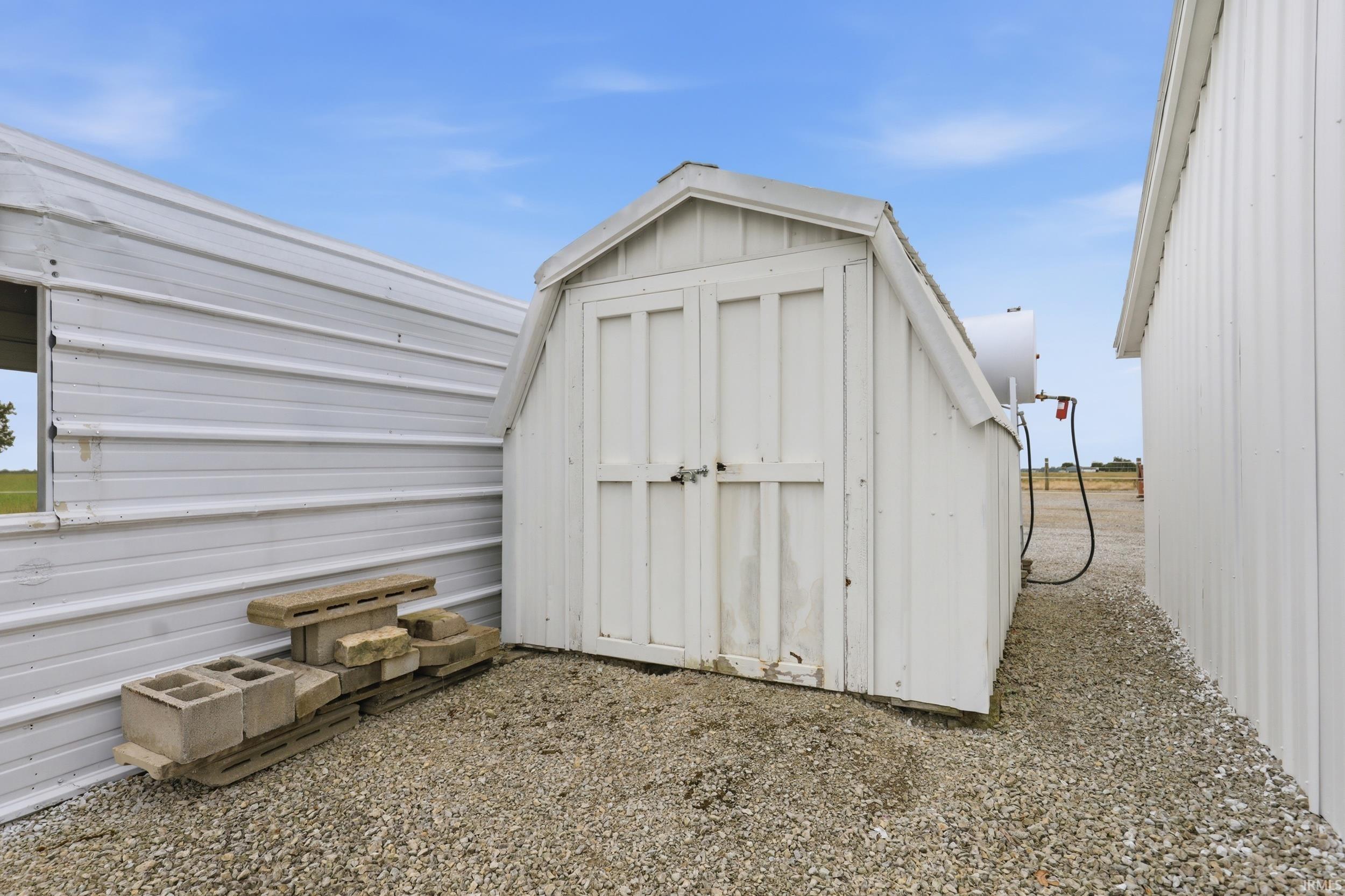 White wood-sided utility shed with gambrel roof