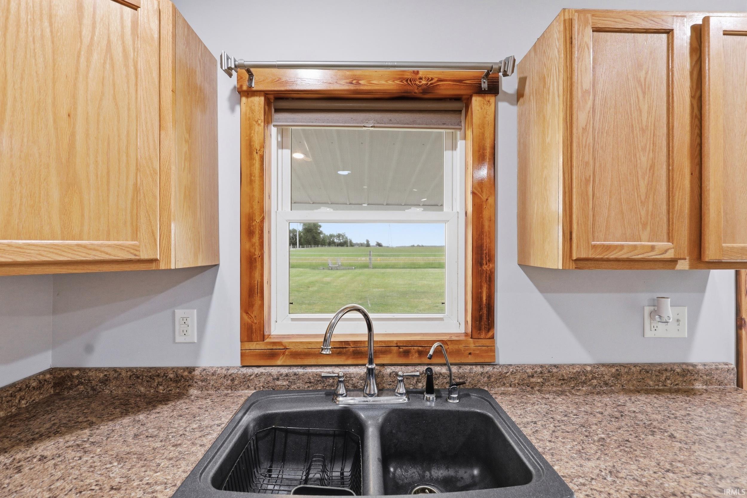 Double basin sink with chrome faucet, complemented by a mottled countertop and light wood cabinetry