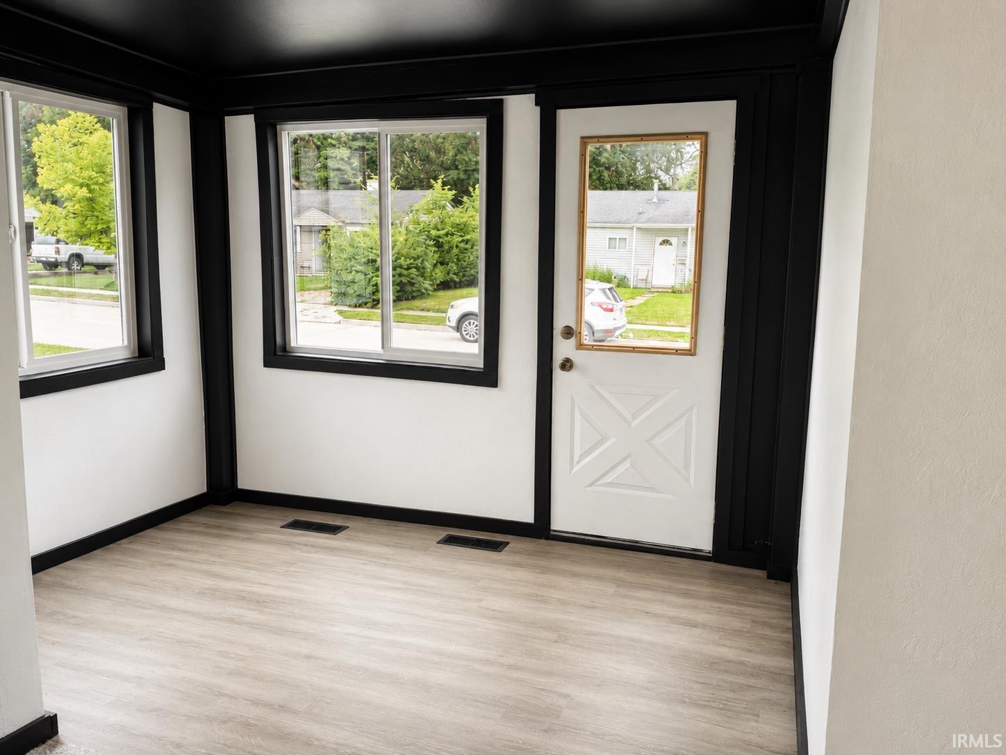 Room featuring wood-finish flooring, white walls, and black trim