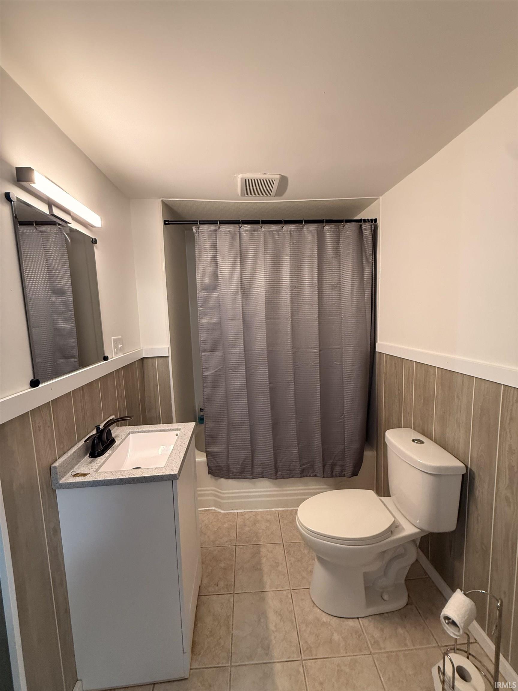 Full bathroom featuring a white vanity with integrated sink, a rectangular mirror, a toilet, and a shower/tub combination