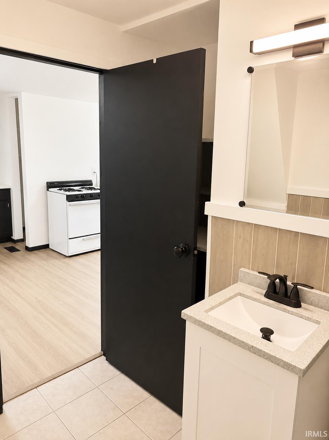 Bathroom vanity featuring a white cabinet, light-colored speckled countertop, and a dark bronze faucet