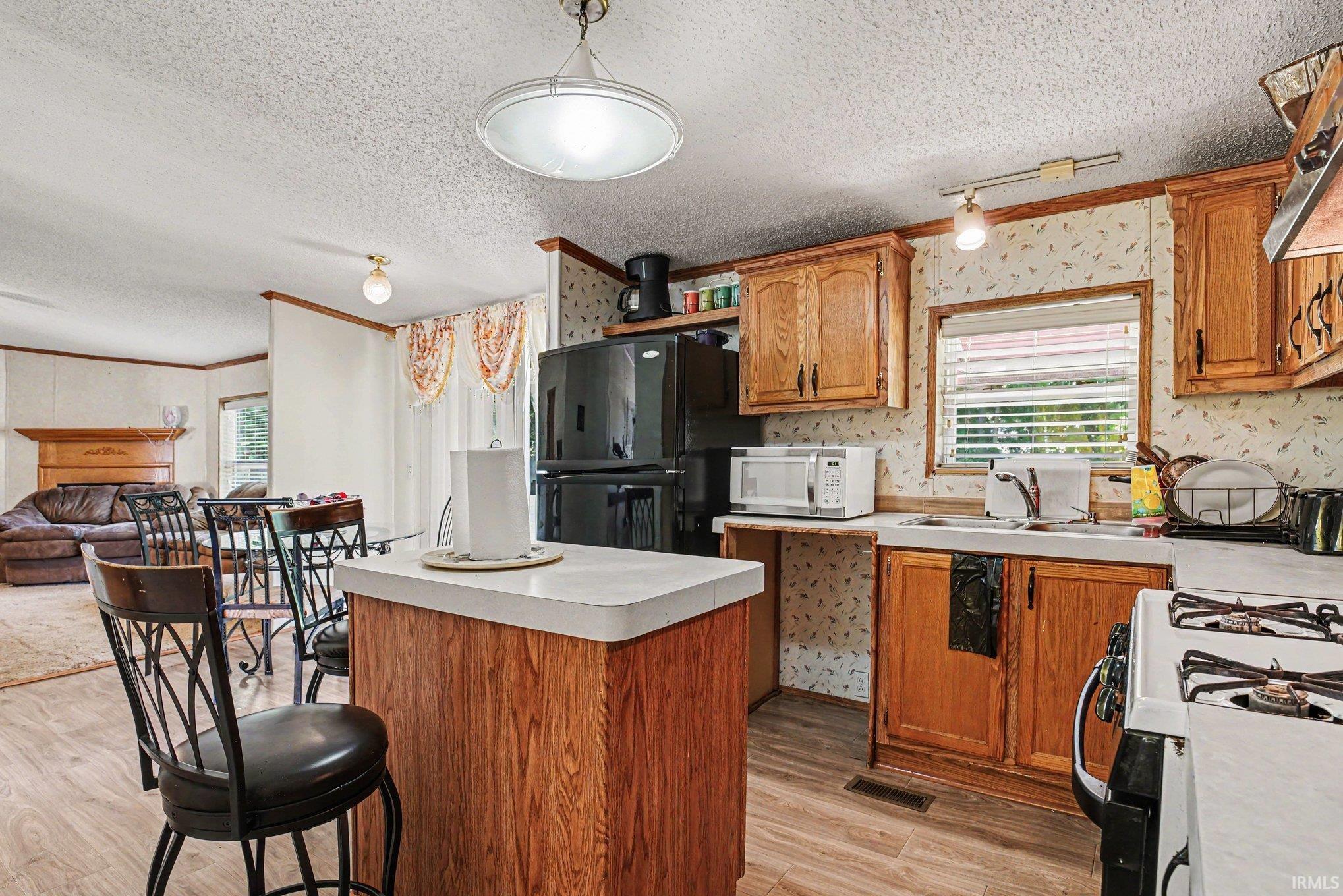 Kitchen featuring wood-finish cabinetry, a central island with countertop, and wood-finish flooring