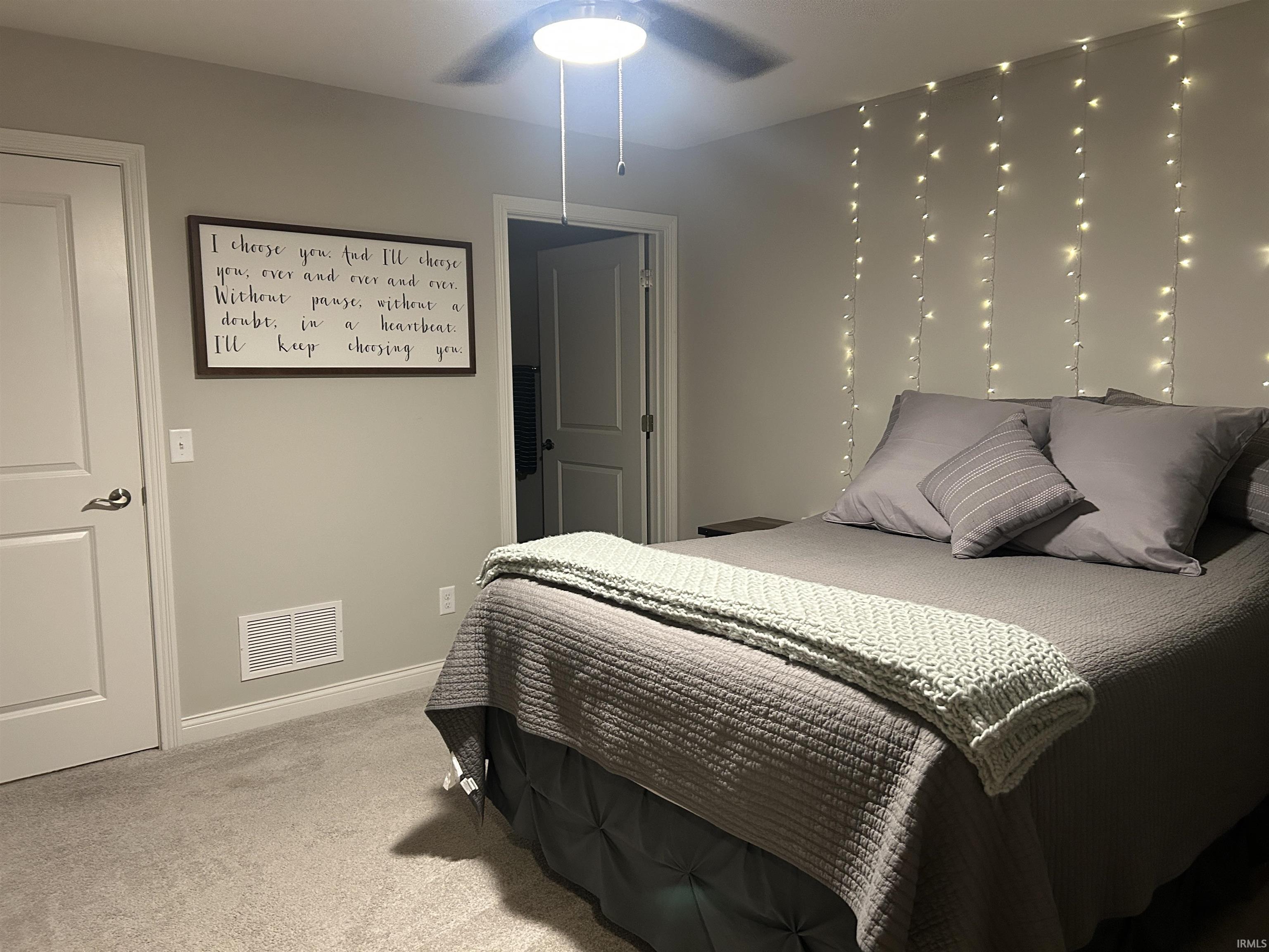 Carpeted room featuring a ceiling fan with integrated lighting, a closed white door with a dark handle, and light gray wall paint