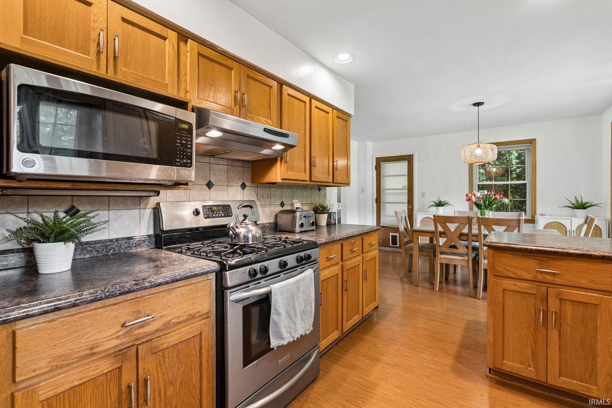 Kitchen with wood-finish flooring, oak cabinetry, and dark countertops