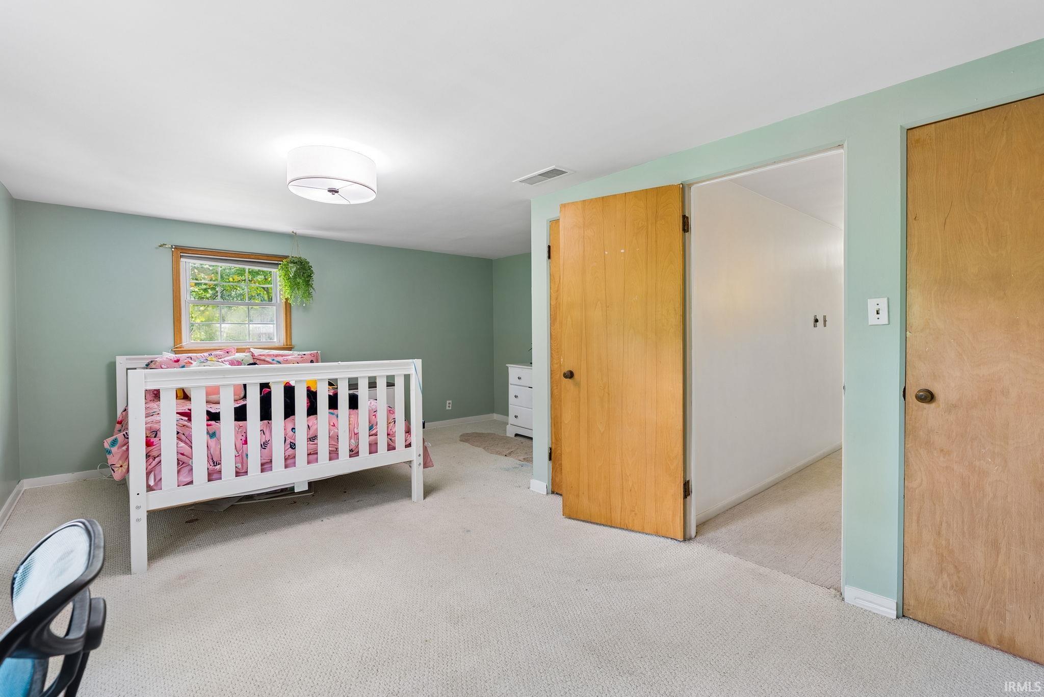 Spacious room featuring light green walls, a window with wood trim, and a ceiling-mounted drum light fixture