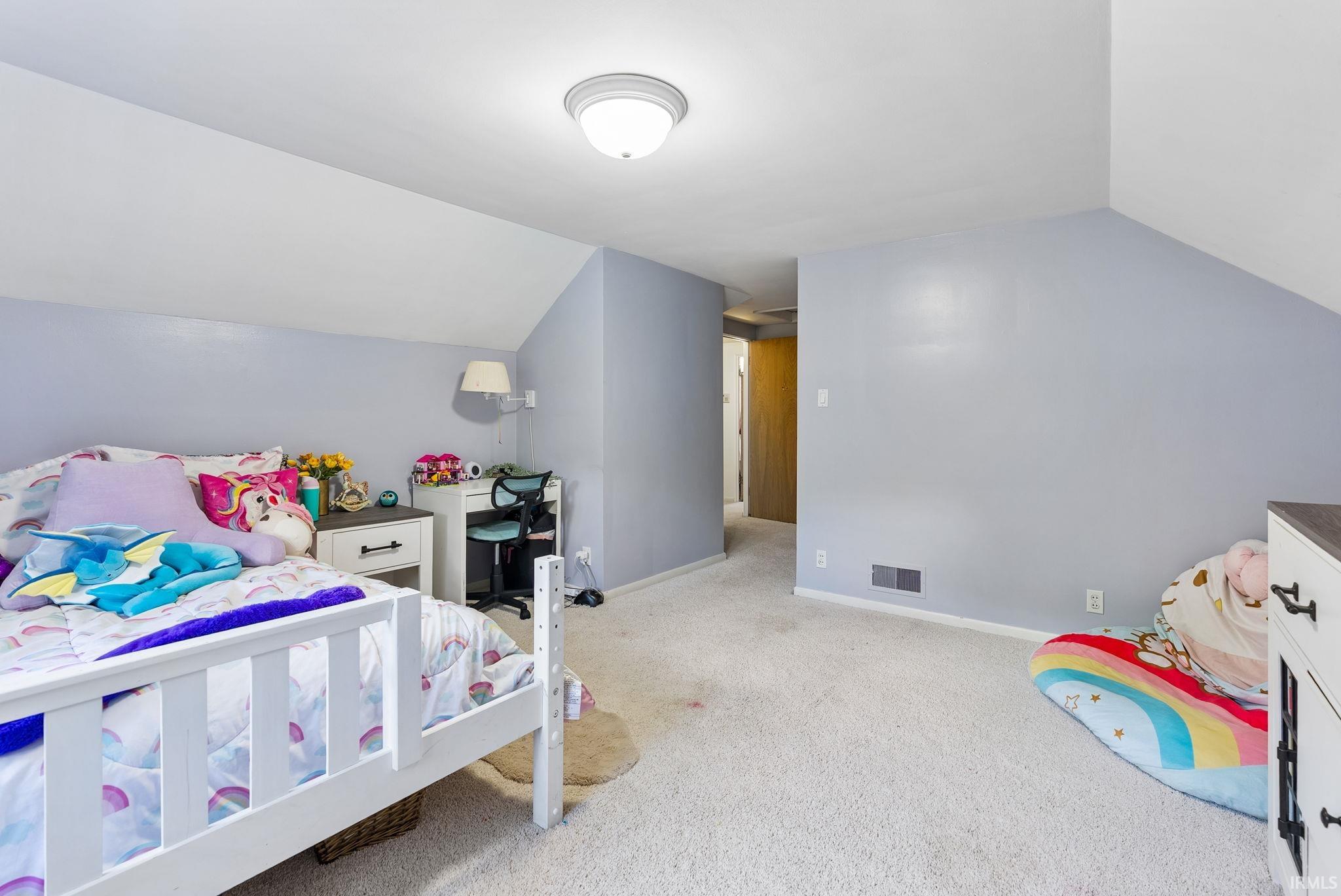 Attic room featuring sloped ceilings, light-toned carpeting, and a flush-mount ceiling light fixture