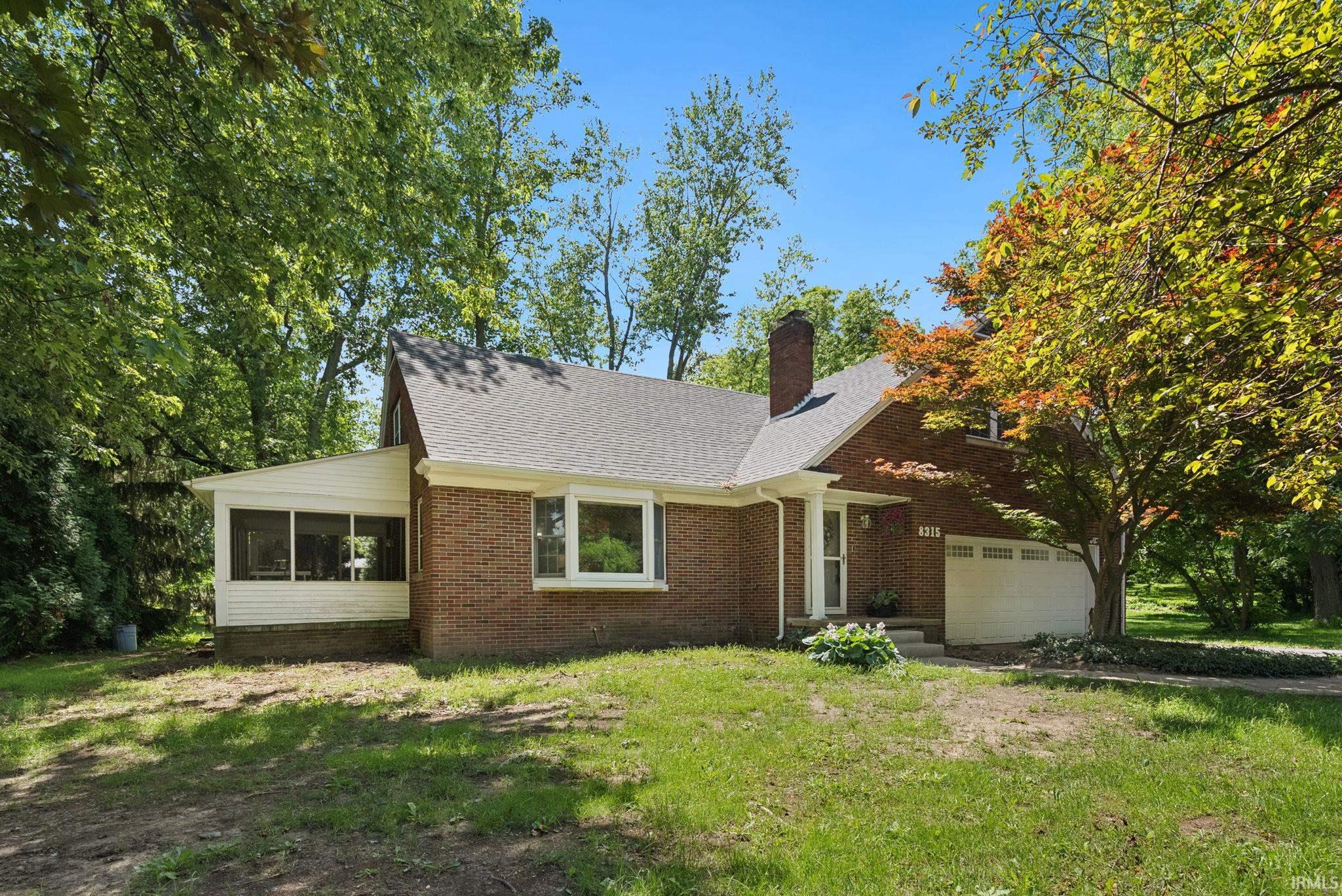 Brick-clad home featuring a screened porch, prominent chimney, and an attached two-car garage