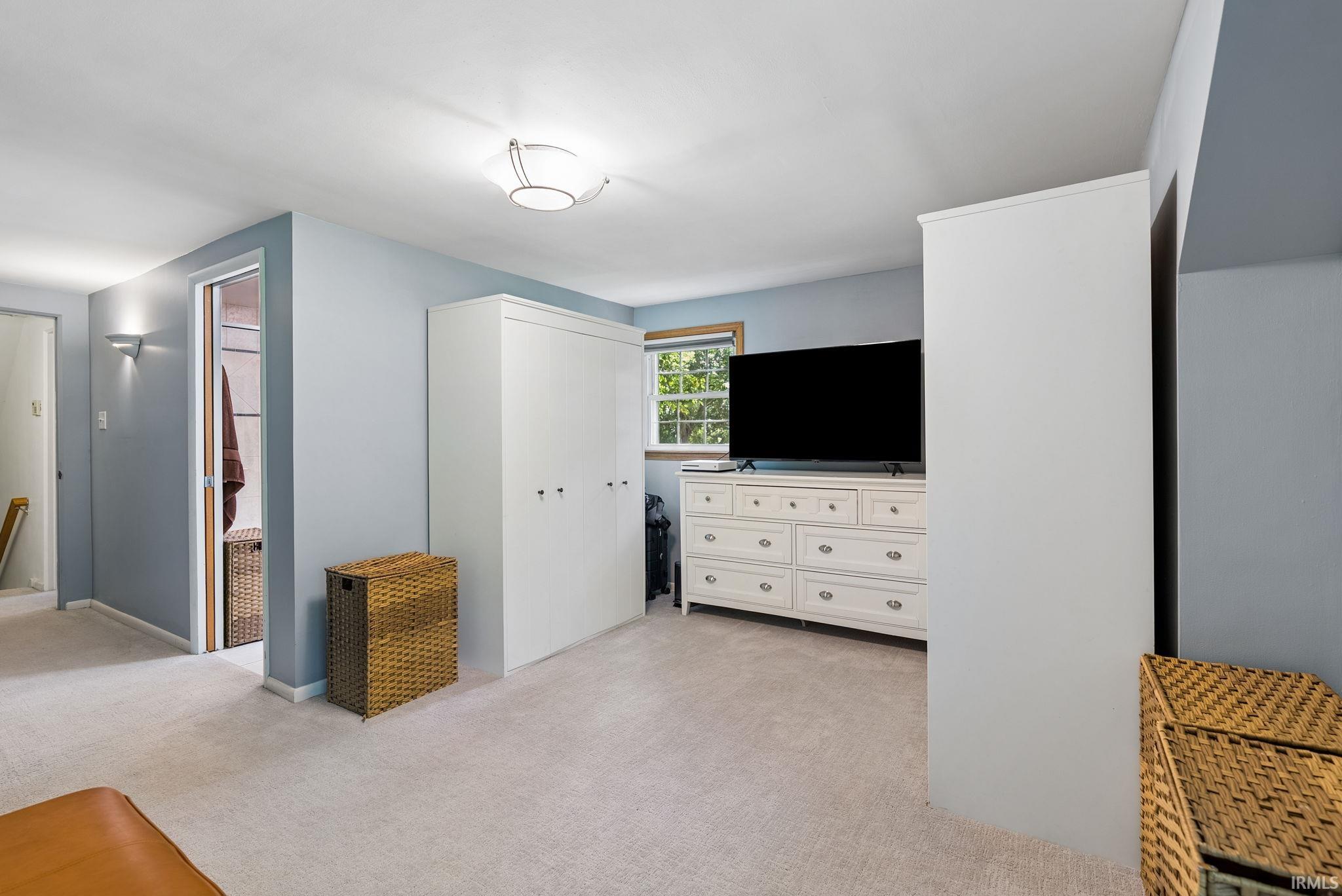 Recessed wall sconce lighting complements the ceiling-mounted fixture, illuminating the light gray carpeting