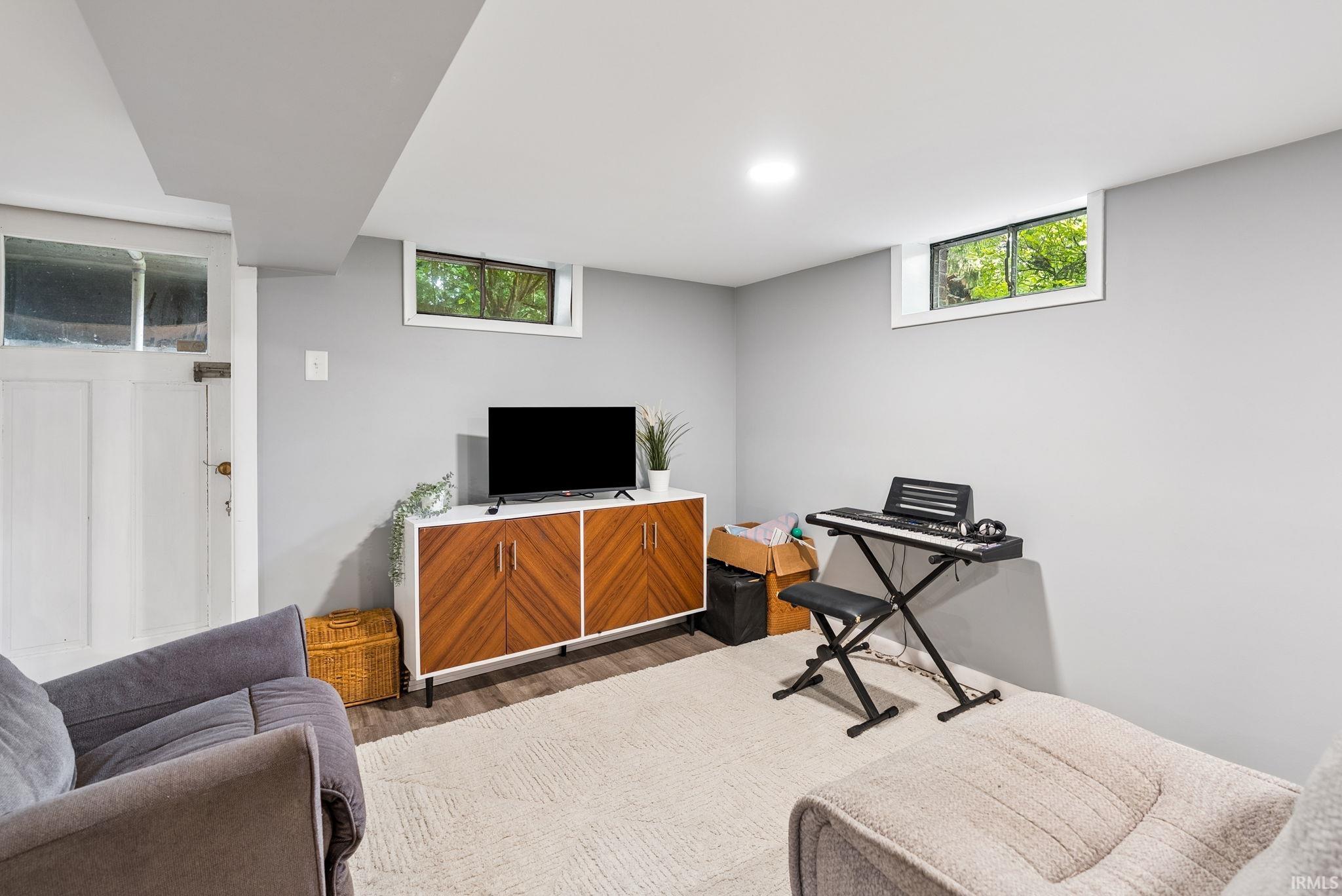 Bright lower-level room featuring light gray walls, recessed lighting, and two high-set windows