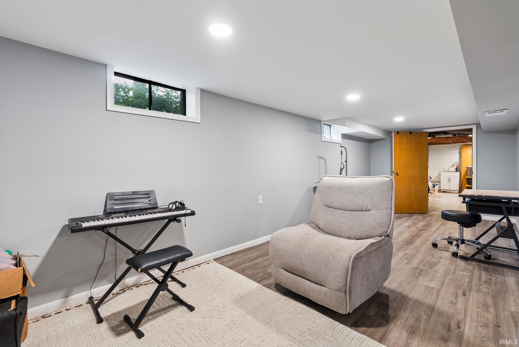 Finished lower level featuring recessed lighting, light gray wall paint, and wood-finish flooring