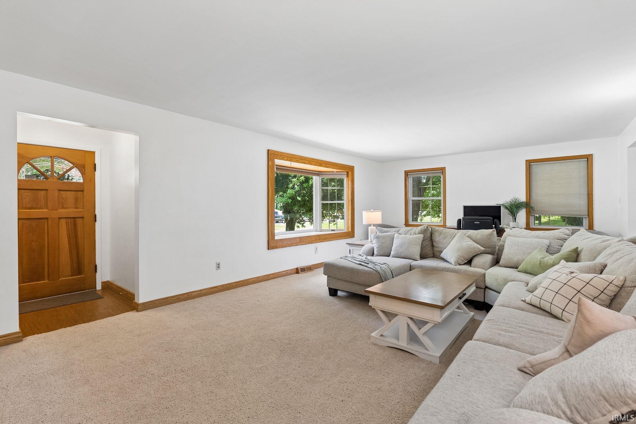 Expansive living area featuring light-toned carpeting and white walls