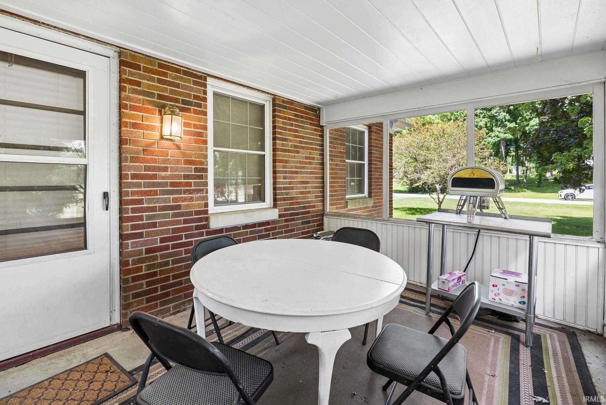 Enclosed porch featuring a painted wood-slat ceiling, exposed brick wall, and screened panels