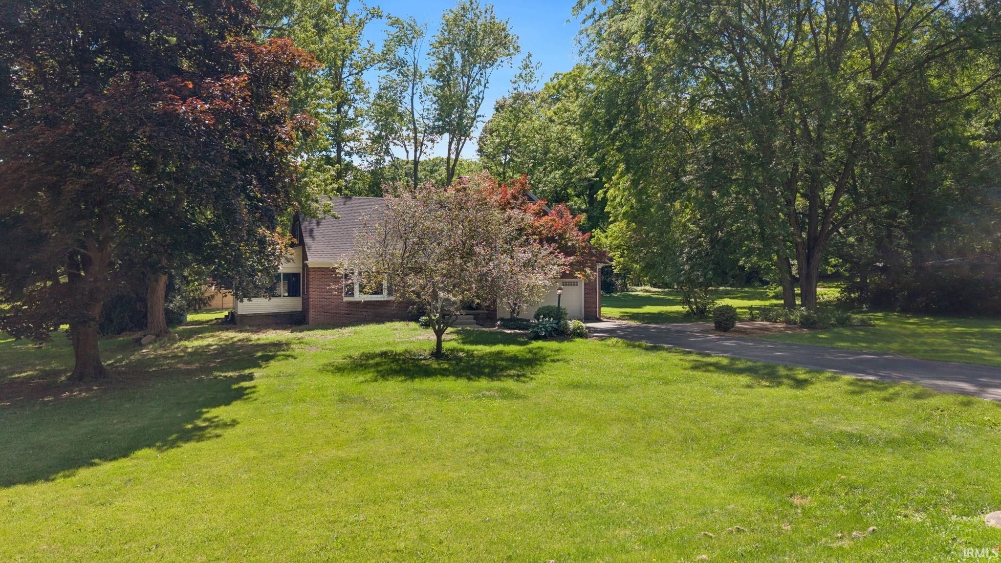 Brick-front residence with a gabled roofline, multiple windows, and a paved driveway