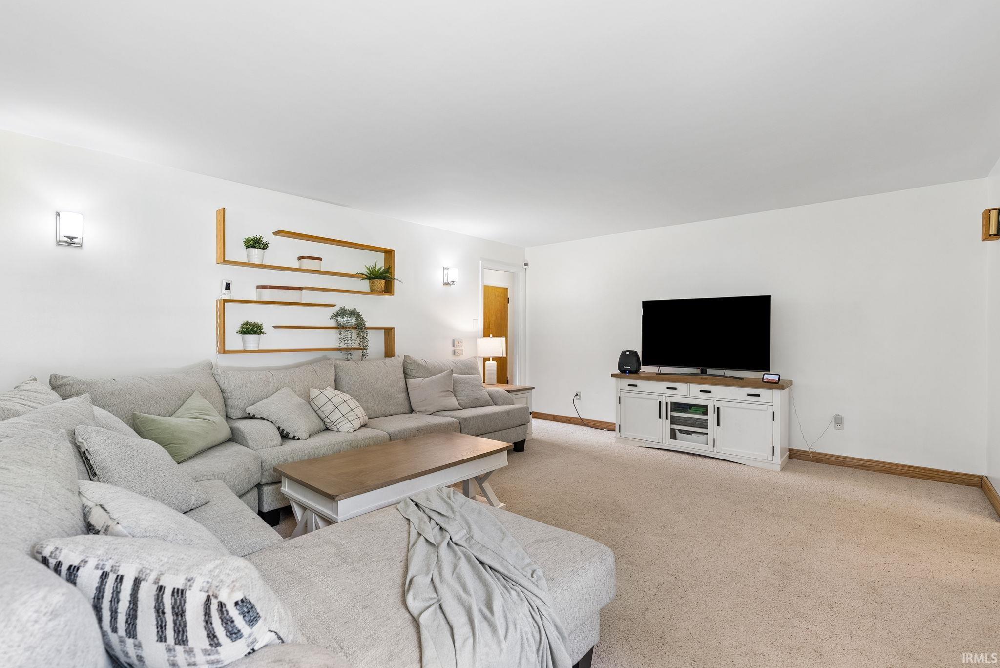 Expansive living area featuring light-toned carpeting and white walls