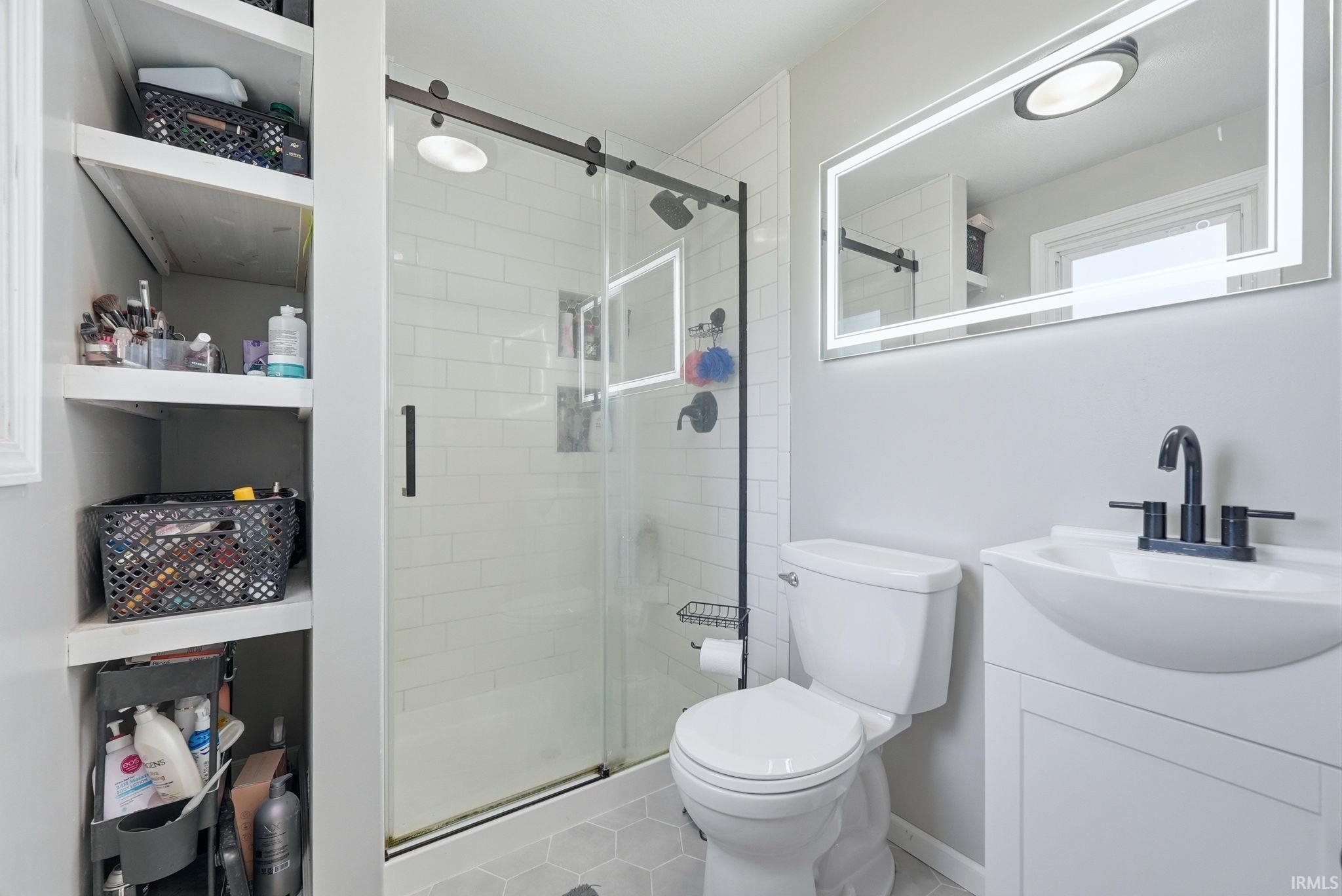 Modern bathroom featuring a glass-enclosed shower with matte black hardware, white subway tile surround, and a coordinating matte black rainfall showerhead