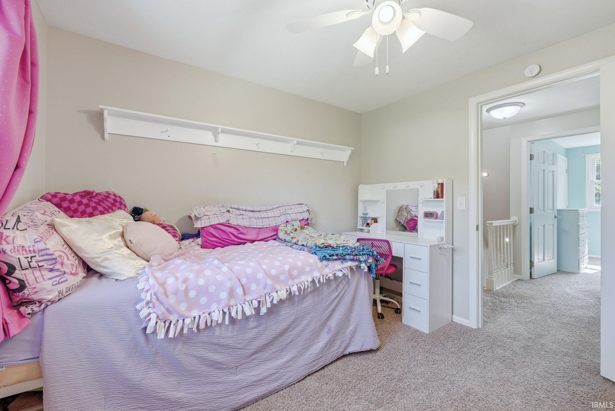 Carpeted room with a ceiling fan, light-toned walls, and a built-in wall shelf