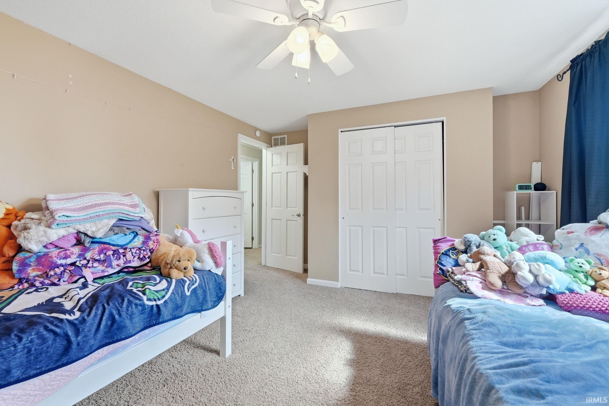 Carpeted room featuring a ceiling fan with light, bi-fold closet doors, and a paneled interior door