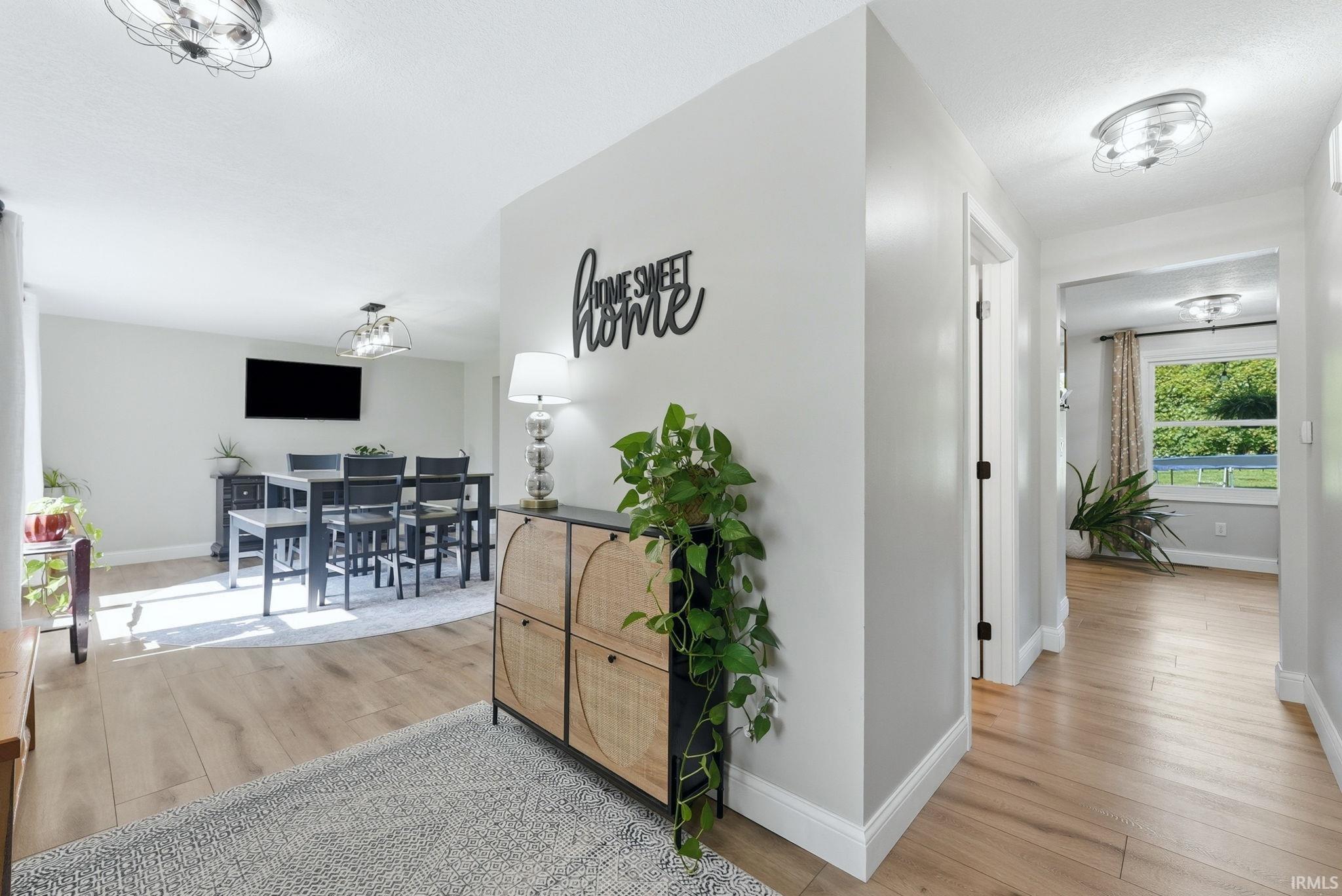 Light wood-finish flooring extending through an entry hall and into a dining area