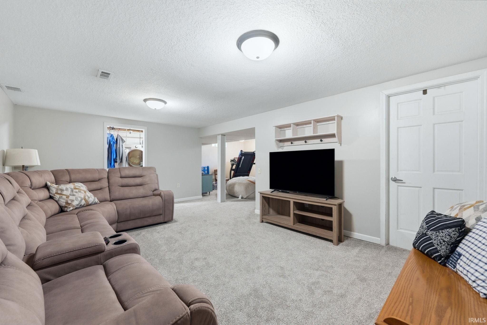Spacious recreation room featuring light gray walls, plush gray carpeting, and recessed lighting fixtures