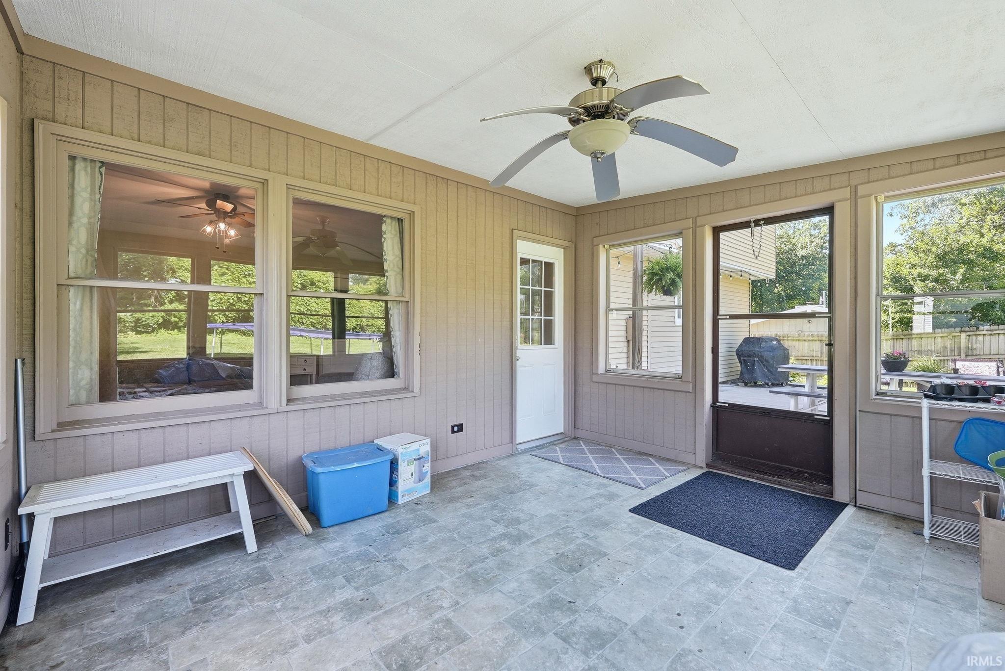 Enclosed sunroom featuring multiple windows, ceiling fan, and tile-finish flooring