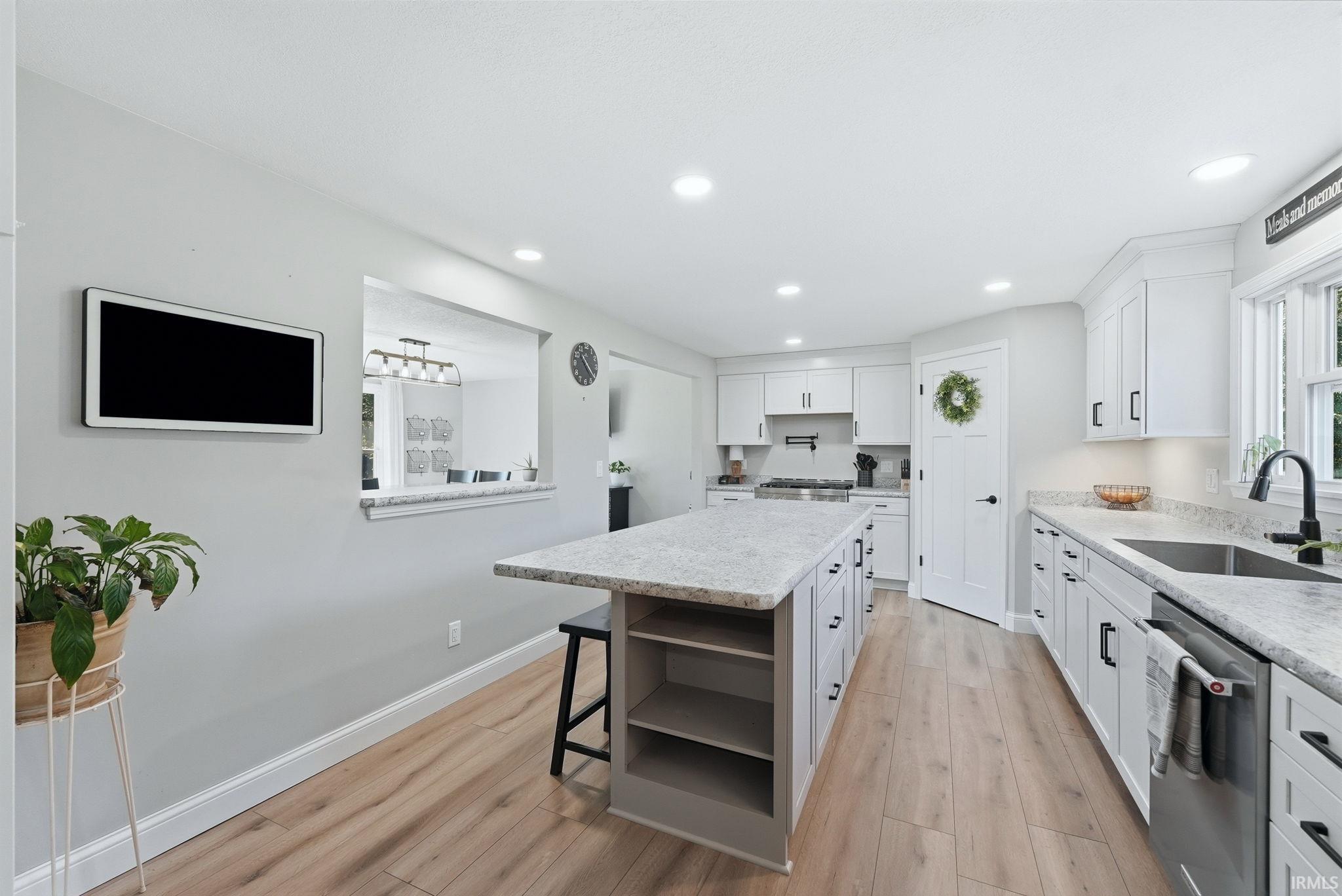 Contemporary kitchen featuring light wood-finish flooring, white cabinetry, and light-toned countertops