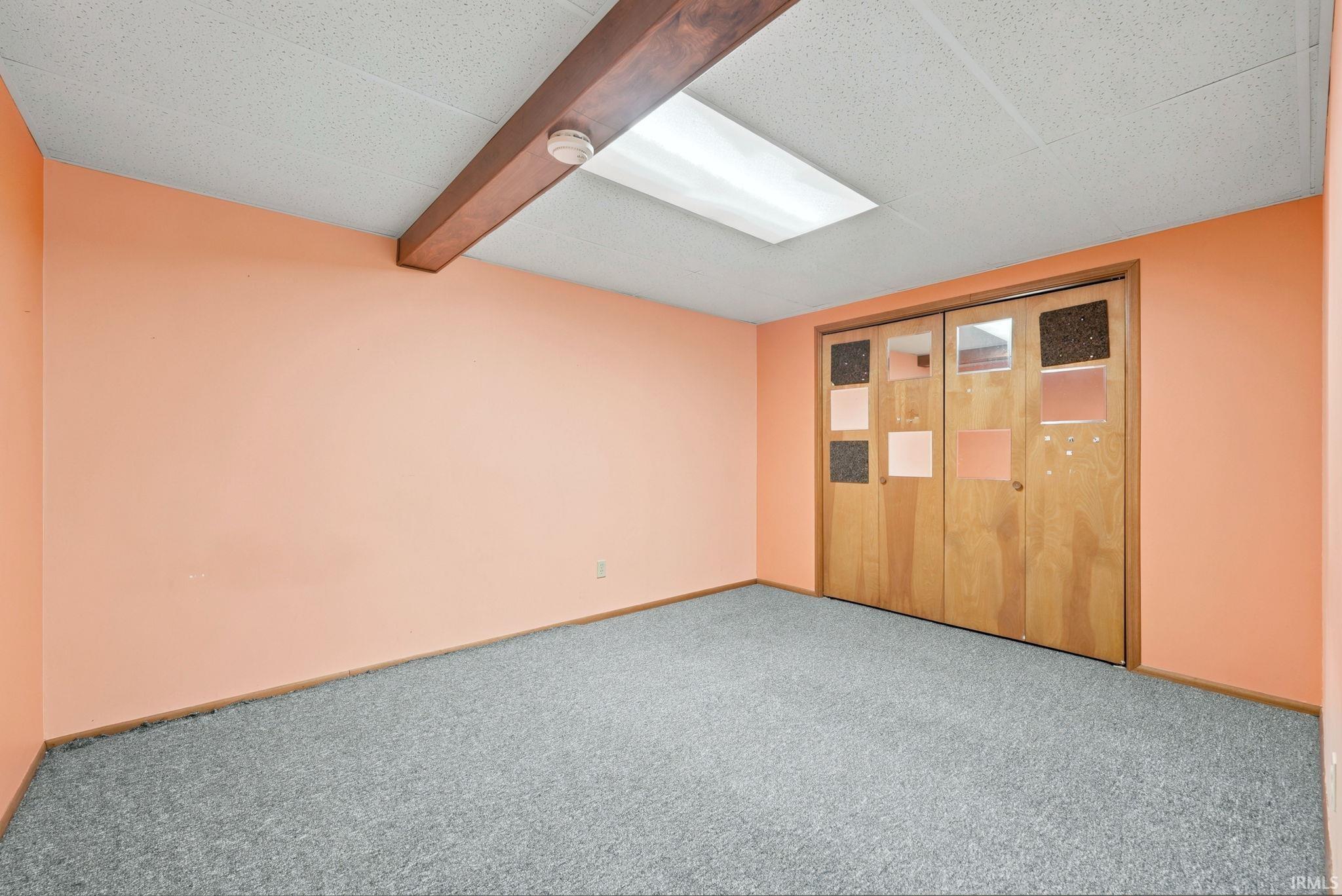 Spacious room featuring peach-toned walls and gray carpeting