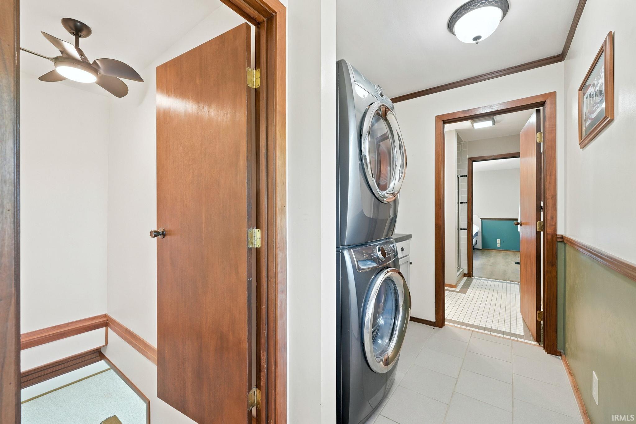 Laundry area featuring stacked appliances, tile flooring, and a flush mount light fixture