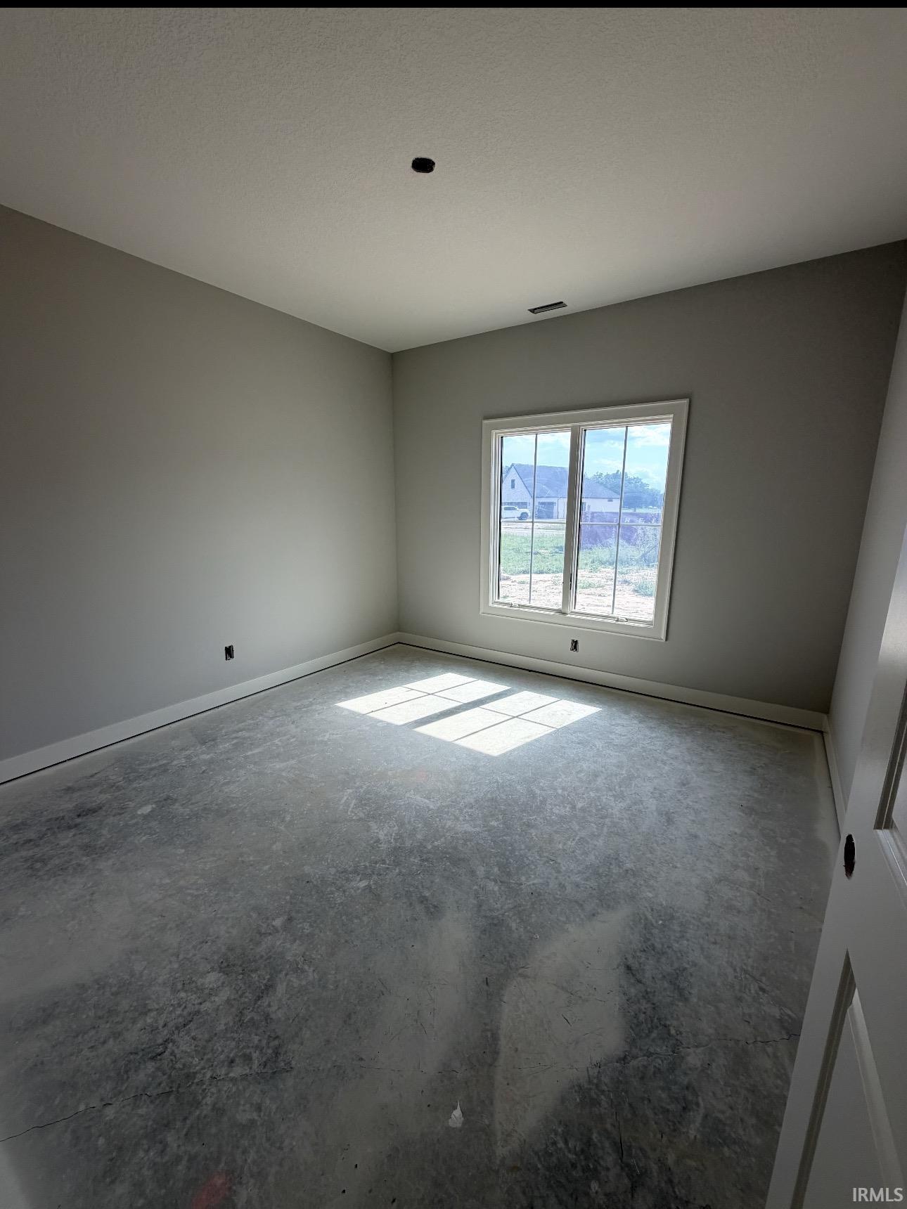Room featuring light gray walls, a single window with white trim, and concrete flooring