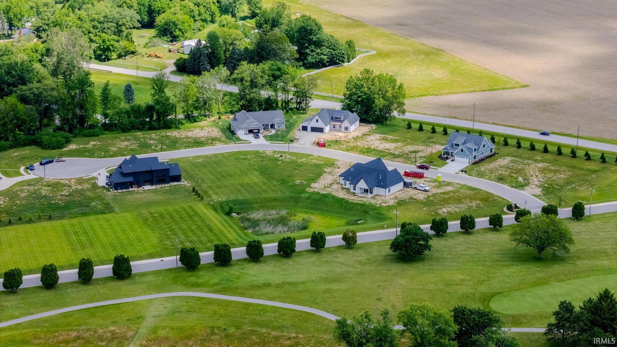 Expansive residential development featuring multiple single-story homes with attached garages, paved driveways, and surrounding green spaces