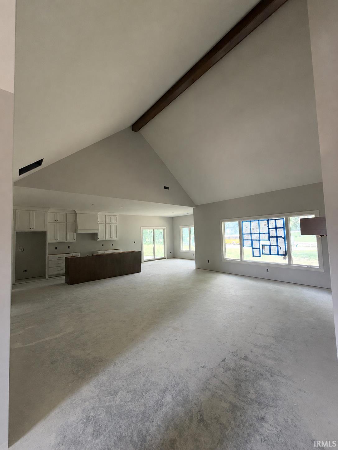 Expansive open-concept living space featuring a vaulted ceiling with an exposed beam