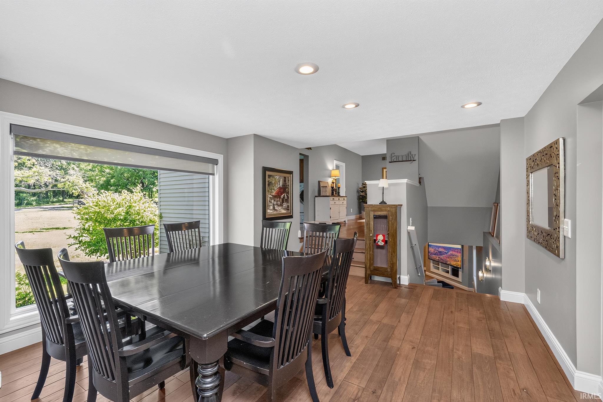 Spacious dining area featuring wood-finish flooring, recessed lighting, and a large window