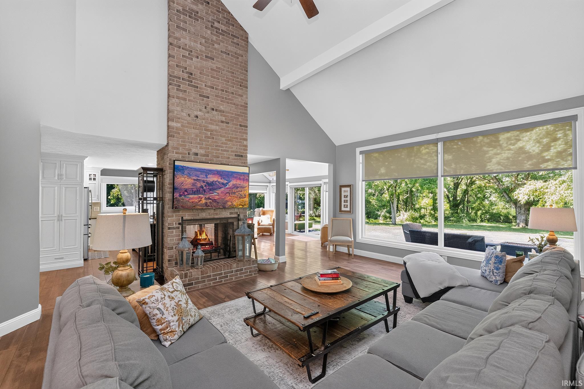 Vaulted ceiling living area featuring a prominent brick fireplace with hearth