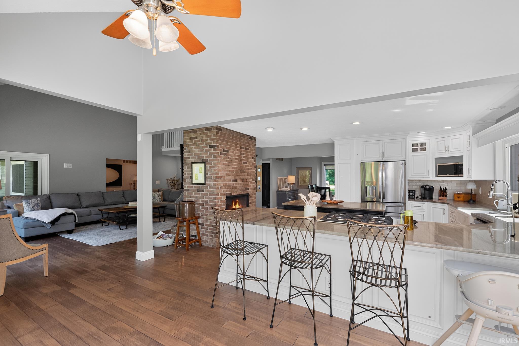 Spacious kitchen featuring white cabinetry, stainless steel appliances, a large island with cooktop, and a breakfast bar
