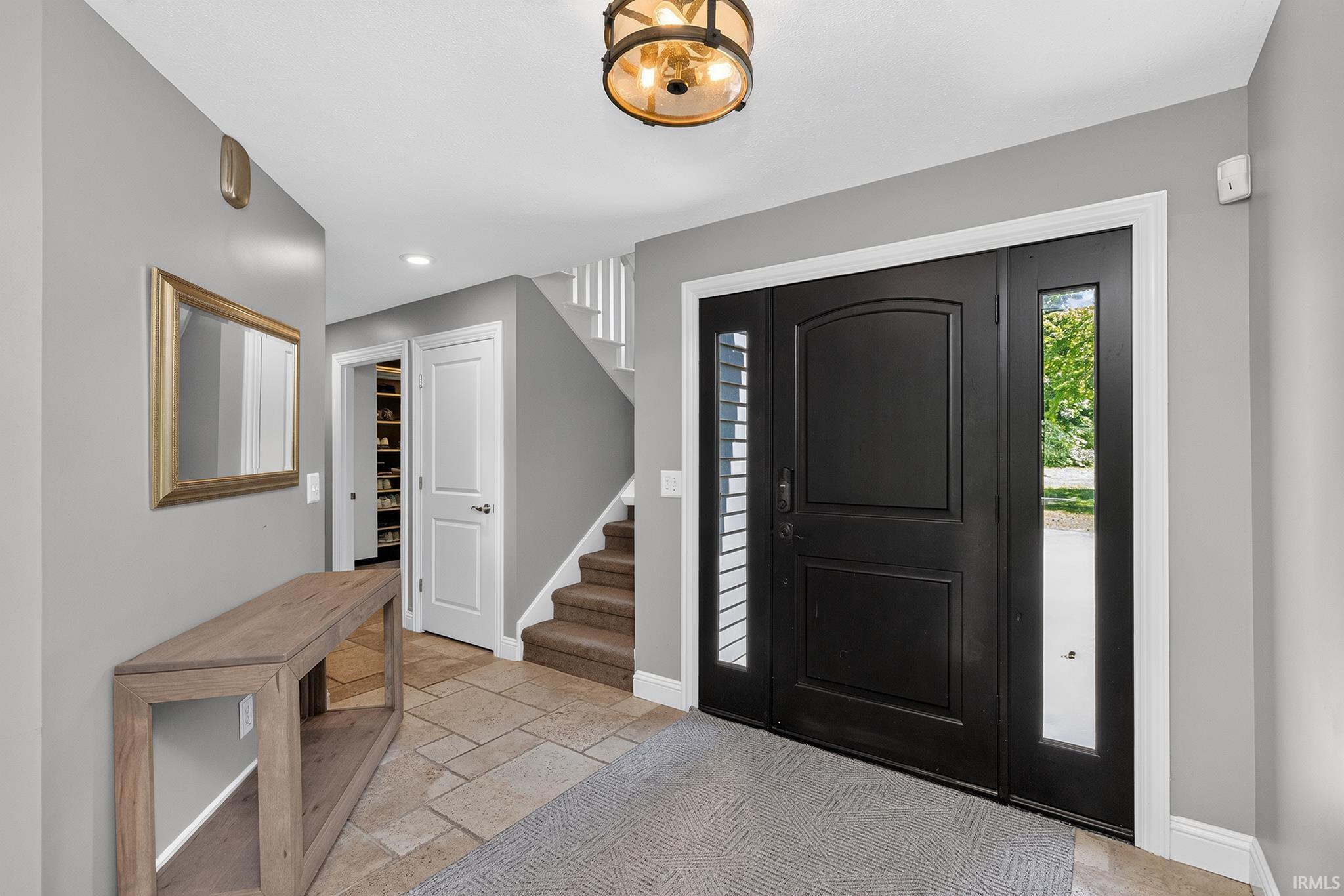 Foyer featuring a dark-paneled entry door with sidelights, a coordinated overhead light fixture, and tile flooring