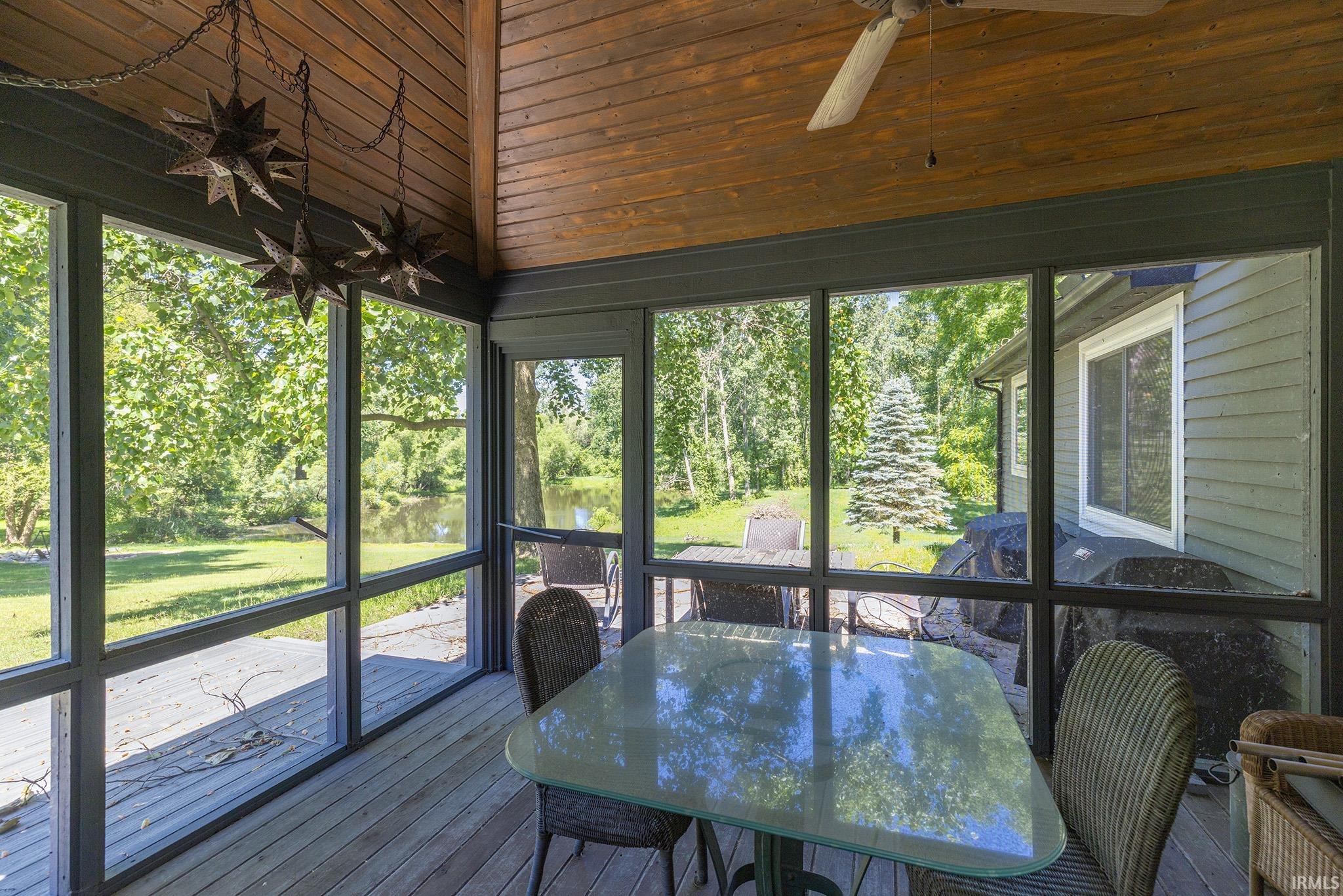Screened porch with wood-finish vaulted ceiling and a ceiling fan