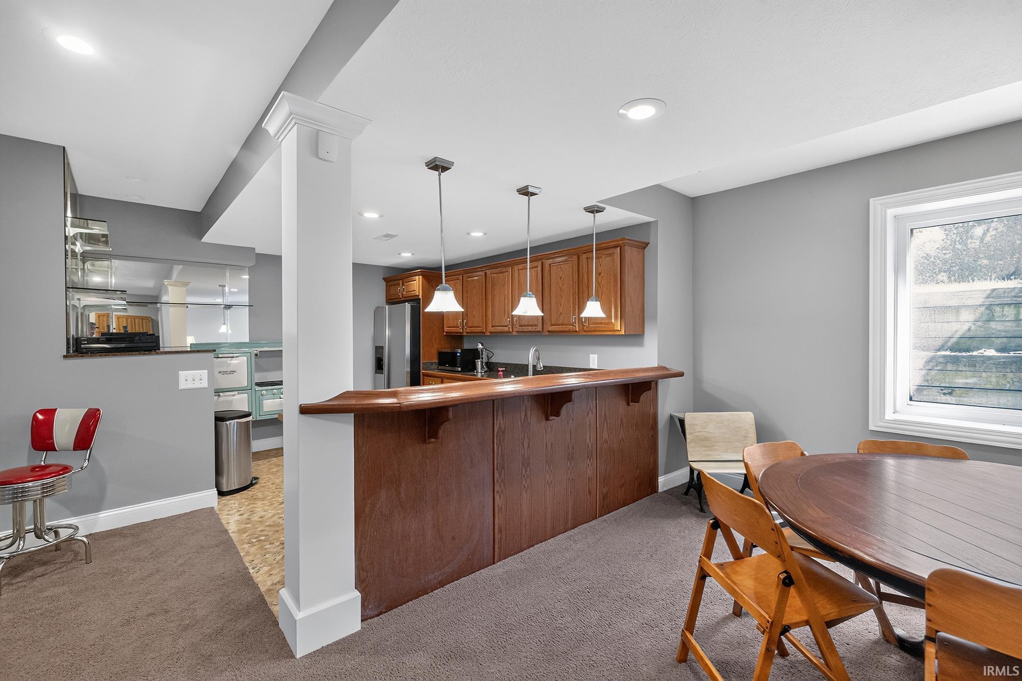 Recreational space featuring a built-in wet bar with wood cabinetry and pendant lighting, carpet flooring, a window, and recessed lighting
