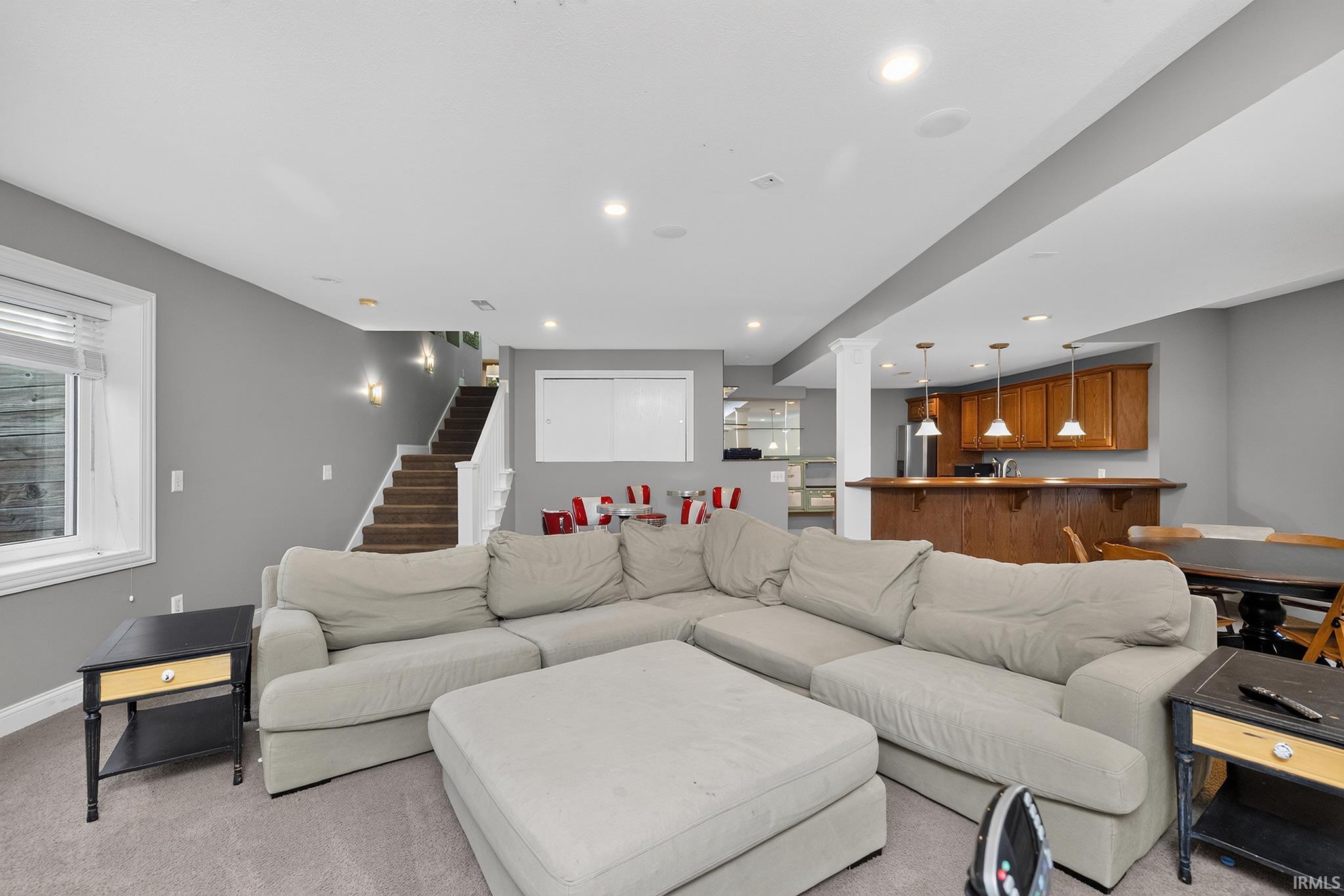 Finished basement living area featuring recessed lighting, a window with white blinds, and carpeted flooring