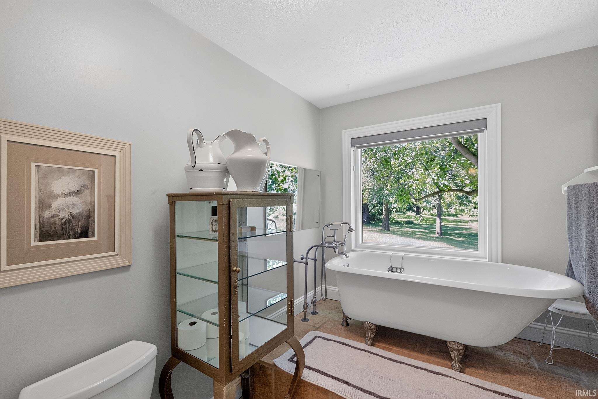Freestanding clawfoot tub with floor-mounted fixtures, set against a large window