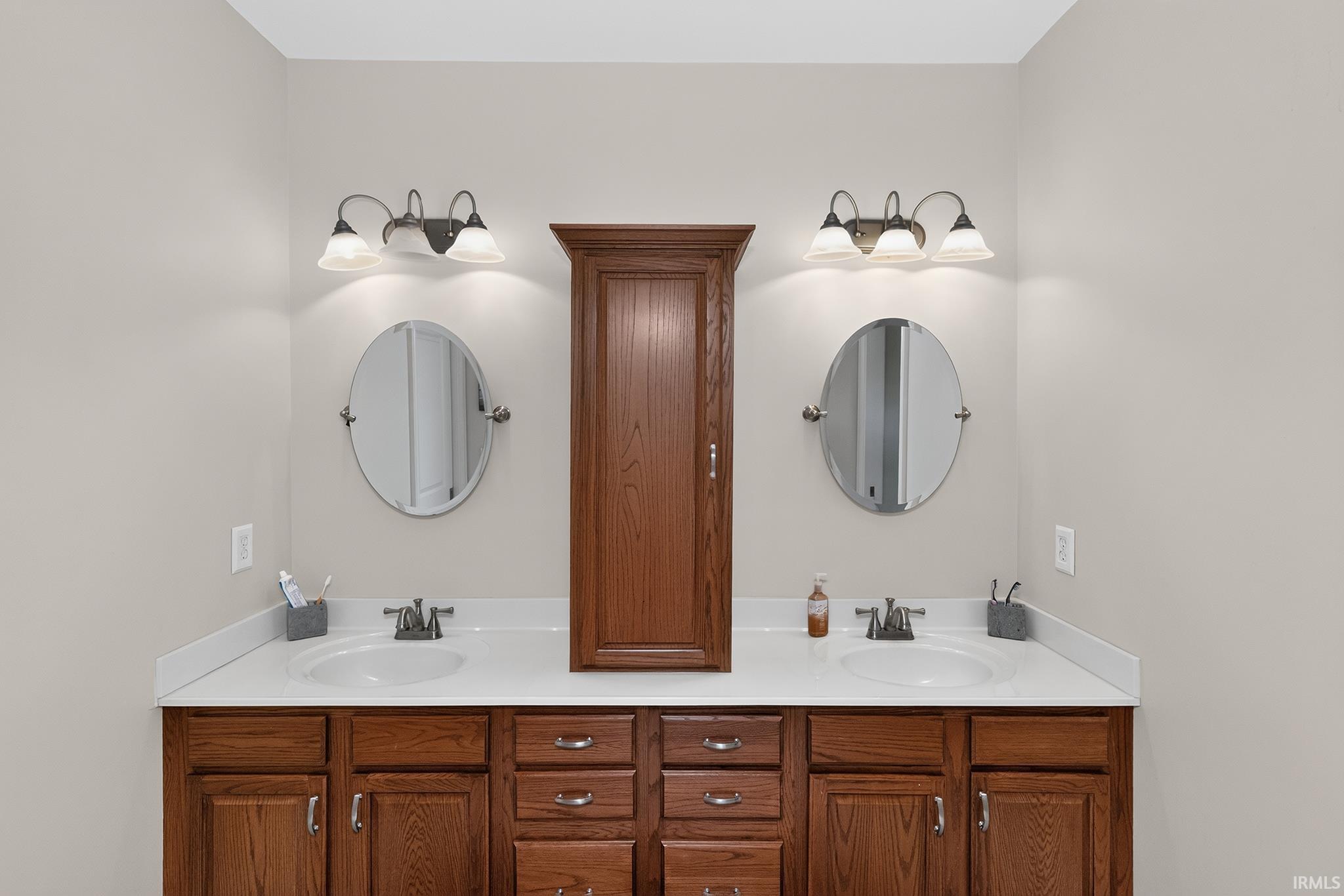 Dual vanity featuring undermount sinks, white countertops, and wood-finish cabinetry