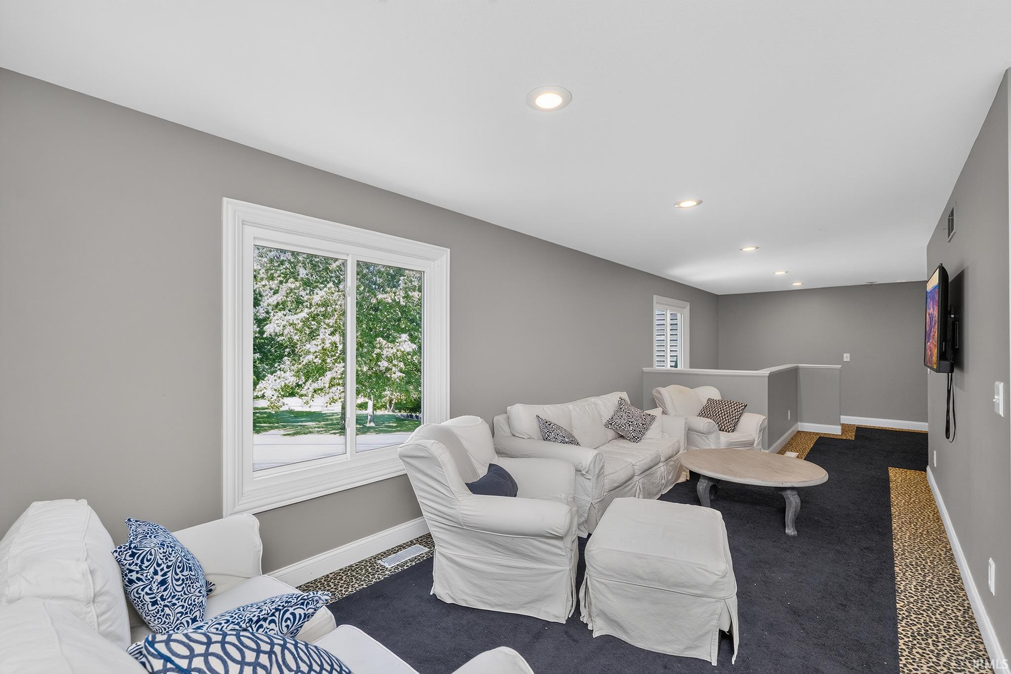 Spacious room featuring a large window, recessed lighting, and a wall-mounted television