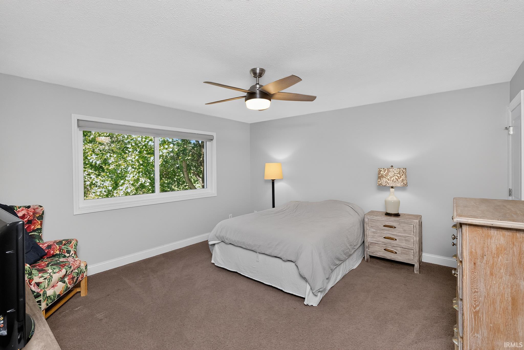 Bedroom featuring wall-to-wall carpeting, light gray walls, a white trim window, a ceiling fan with integrated lighting, and a white door frame