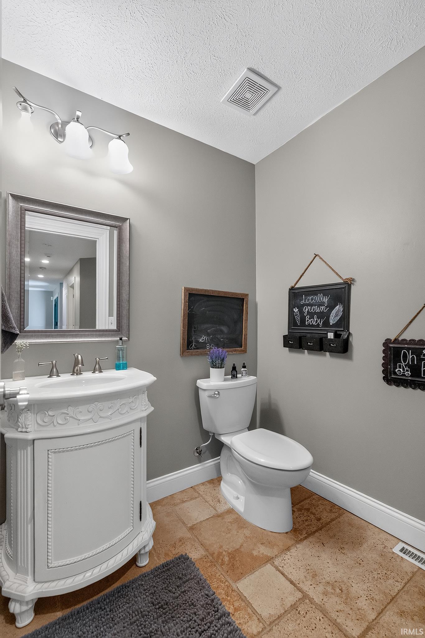 Bathroom featuring a decorative vanity with integrated sink, chrome faucet, framed mirror, and tile flooring