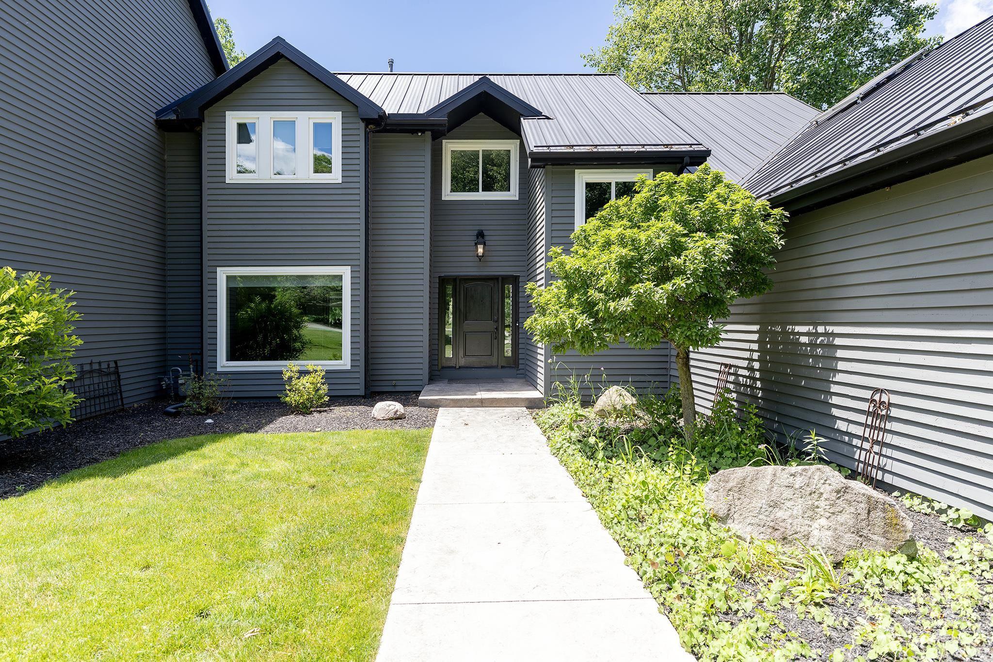 Modern exterior featuring dark gray siding, a metal roof, and white window trim