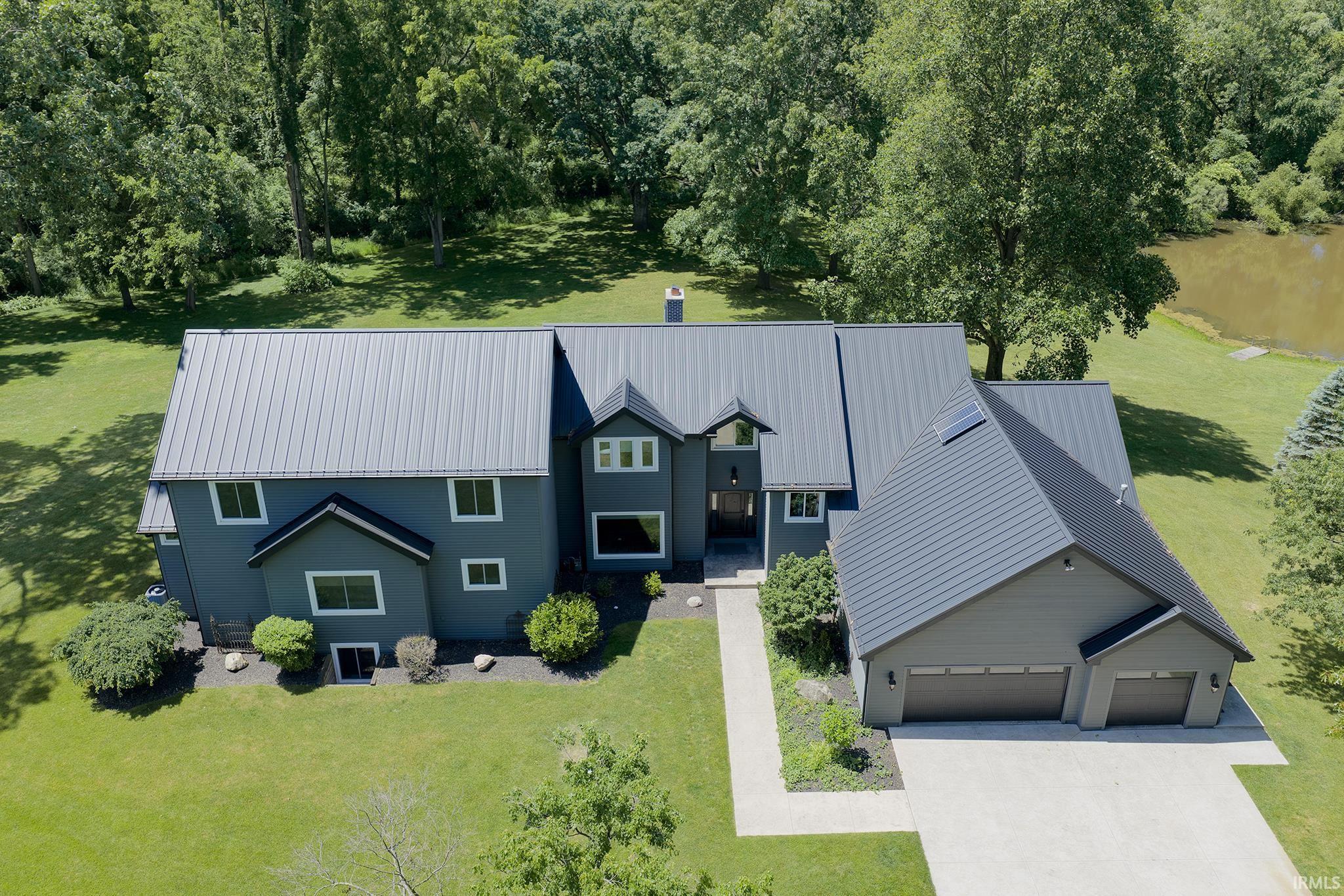 Modern-style residence featuring a dark gray exterior, multiple pitched metal roofs, and a three-car garage