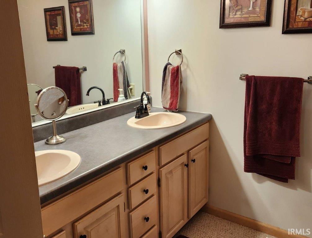 Dual vanity with light wood-finish cabinetry, black hardware, and integrated sinks